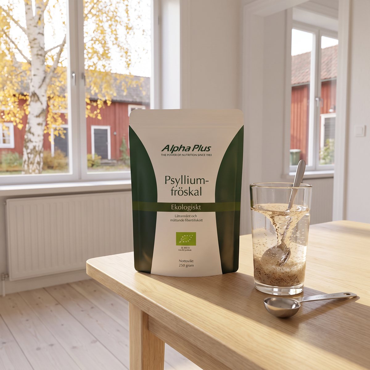 Alpha Plus psylliumpåse på ett köksbord med ett glas rörd psylliumdryck och en måttsked i en svensk bostad