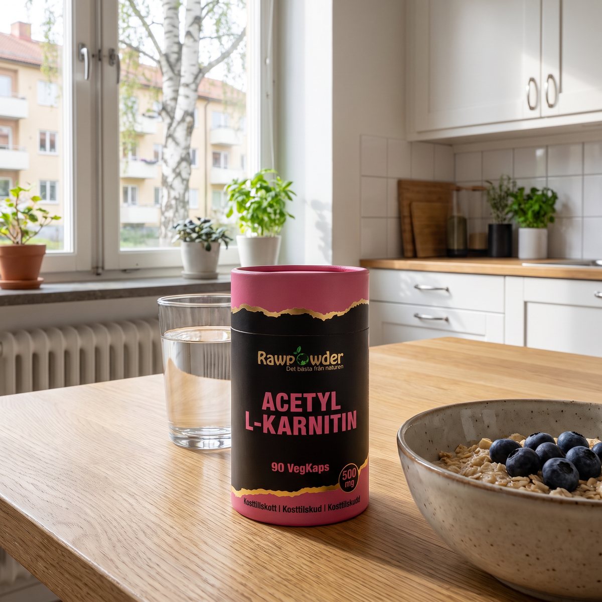 Rawpowders Acetyl L-Karnitin i rosa och svart pappburk på ett ekträbord i ett svenskt kök med havregrynsgröt och ett glas vatten