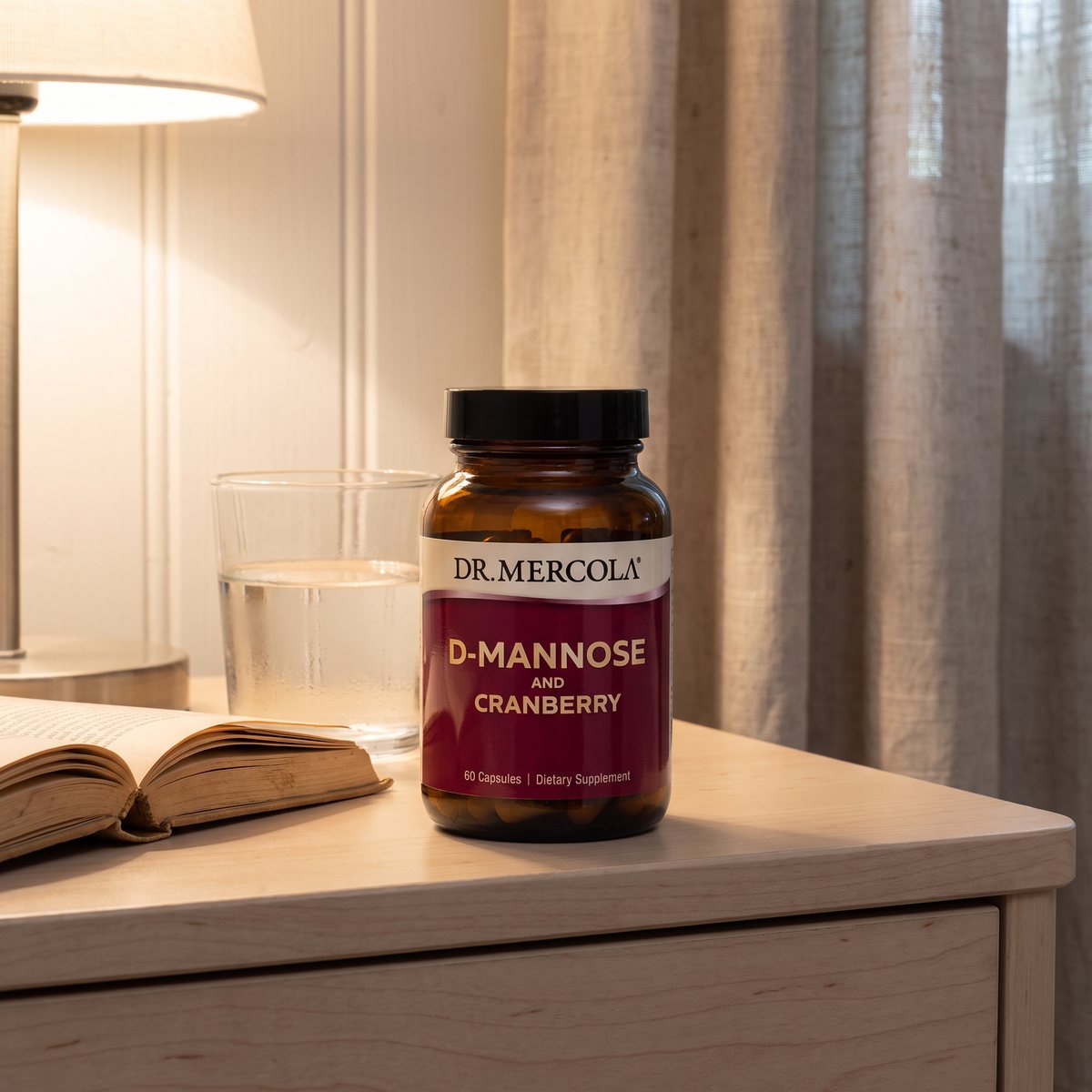 Dr Mercola D-Mannose and Cranberry i brun glasburk på ett sängbord i björk i ett svenskt sovrum, med vattenglas och bok