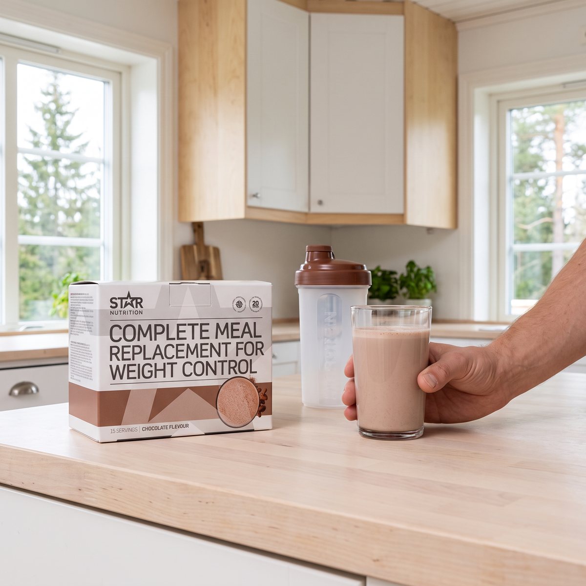 Star Nutrition Complete Meal-kartong med shaker och glas chokladshake på en köksbänk i ett ljust svenskt kök