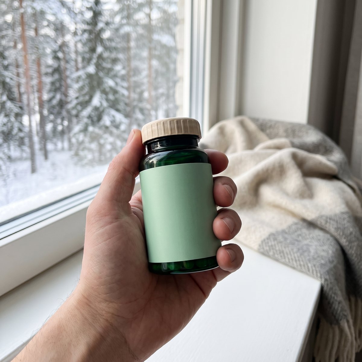 Hand som håller en grön glasburk vid ett fönster i ett svenskt hem