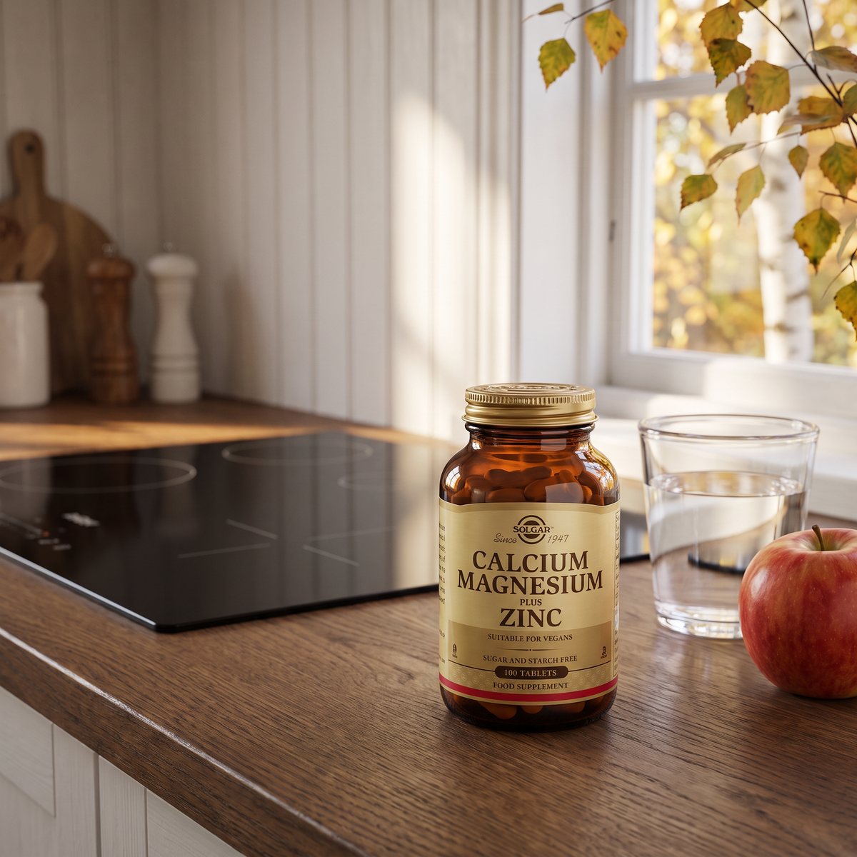 Brun glasburk med Solgar Calcium Magnesium Plus Zinc på en köksbänk i ett svenskt kök med höstlöv utanför fönstret