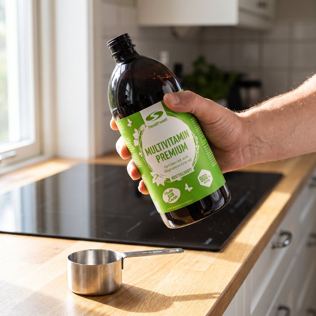 Hand som håller flaskan Healthwell Multivitamin Premium över ett måttglas i ett svenskt kök