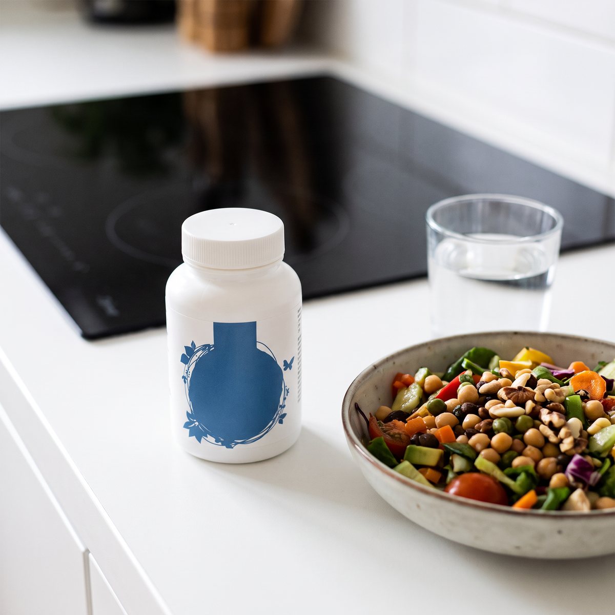 Burk Healthwell Algolja Omega-3 på en köksbänk i ett svenskt kök, bredvid vattenglas och skål med sallad