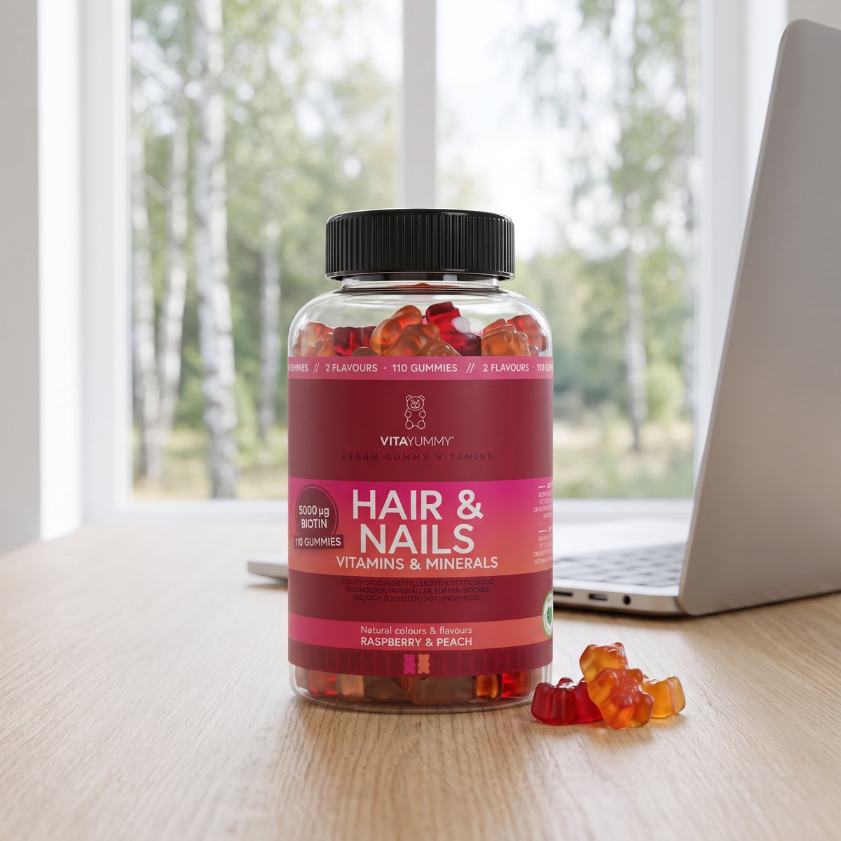 VitaYummy Hair & Nails-burken med gummibjörnar på ett skrivbord vid ett fönster mot björkskog