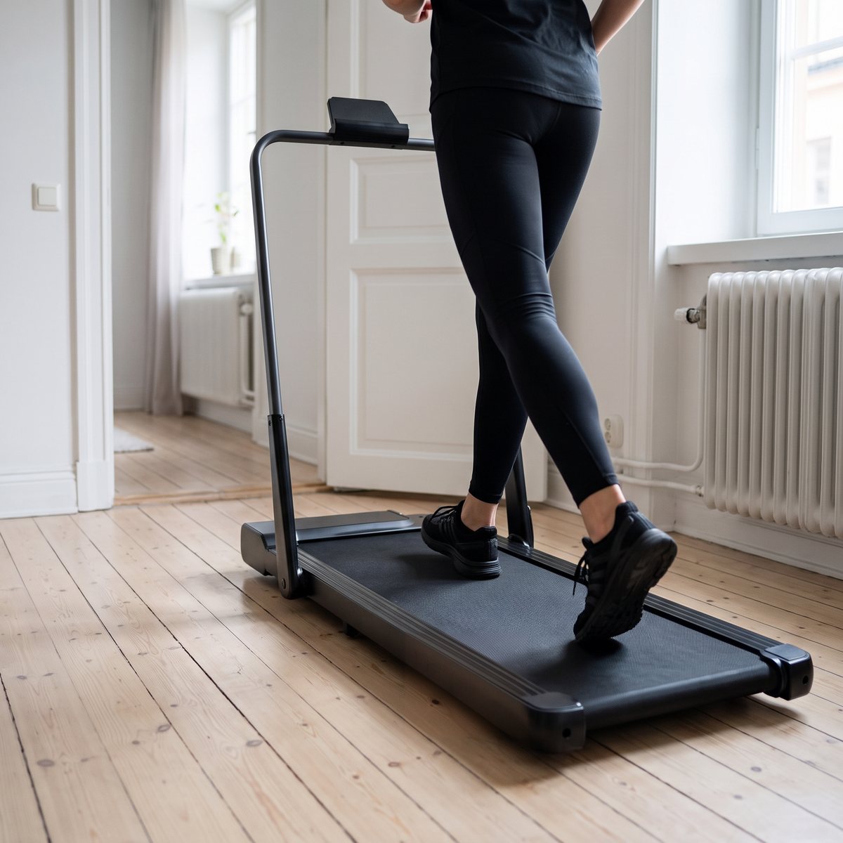 Person joggar på Master Fitness WalkingPad W14 med uppfällt räcke på ett trägolv i en svensk lägenhet