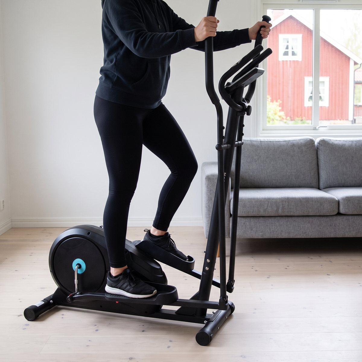 Titan LIFE C35 crosstrainer i ett svenskt vardagsrum med grå soffa och rött trähus utanför fönstret