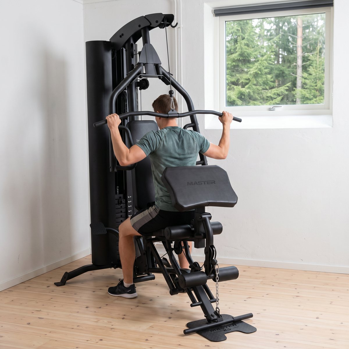 Master Fitness Multigym X5 med viktmagasin i ett ljust svenskt hemmagym med fönster mot granskog, använd för latsdrag