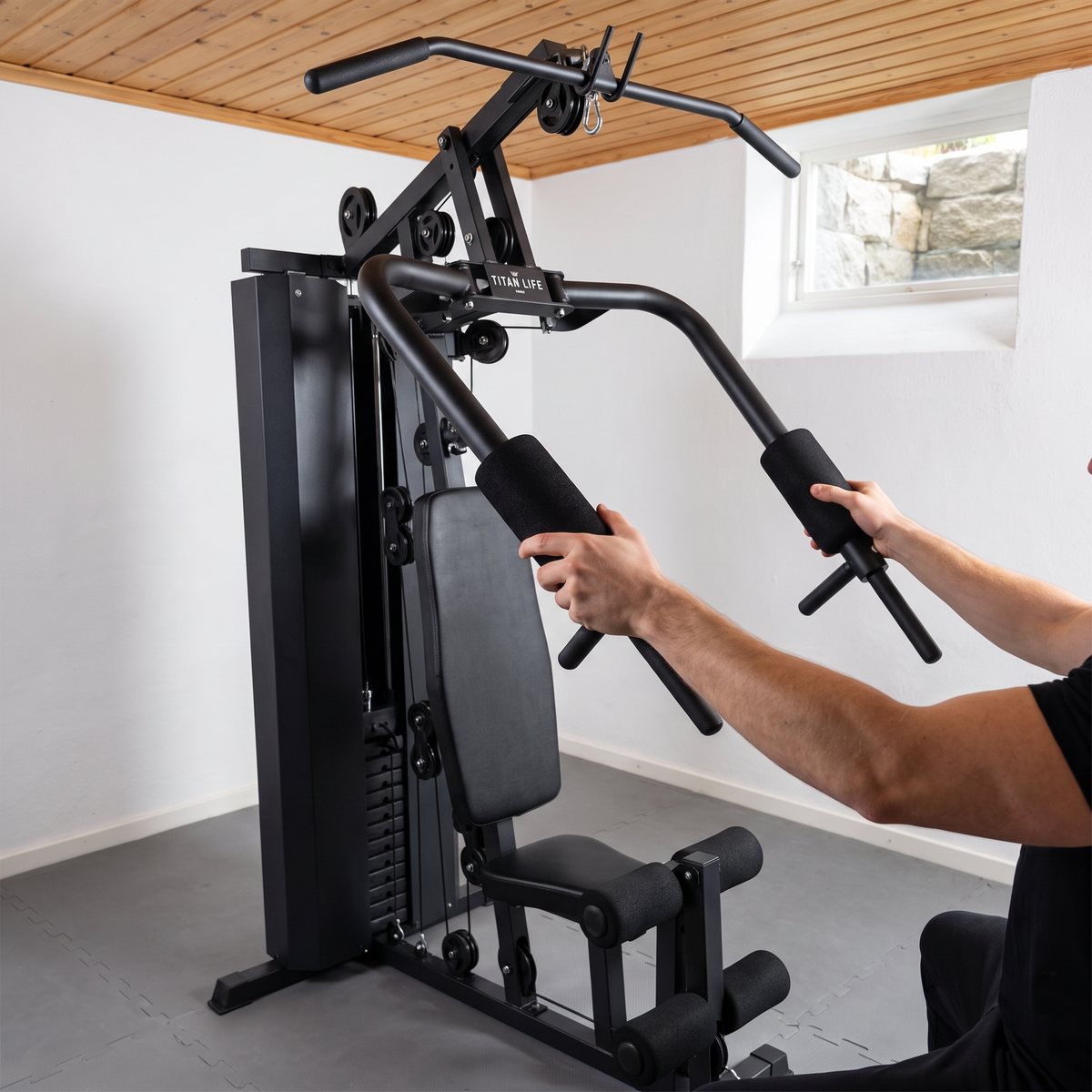 Titan LIFE Homegym 75 kg II i ett svenskt källargym med vit vägg och trätak, använd för bröstpress