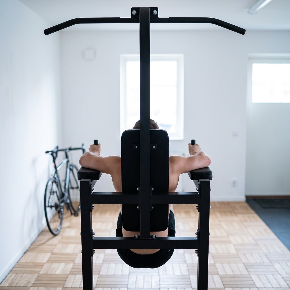 Gorilla Sports Power Tower där en person gör dips med ryggen mot kameran i ett ljust svenskt garagegym