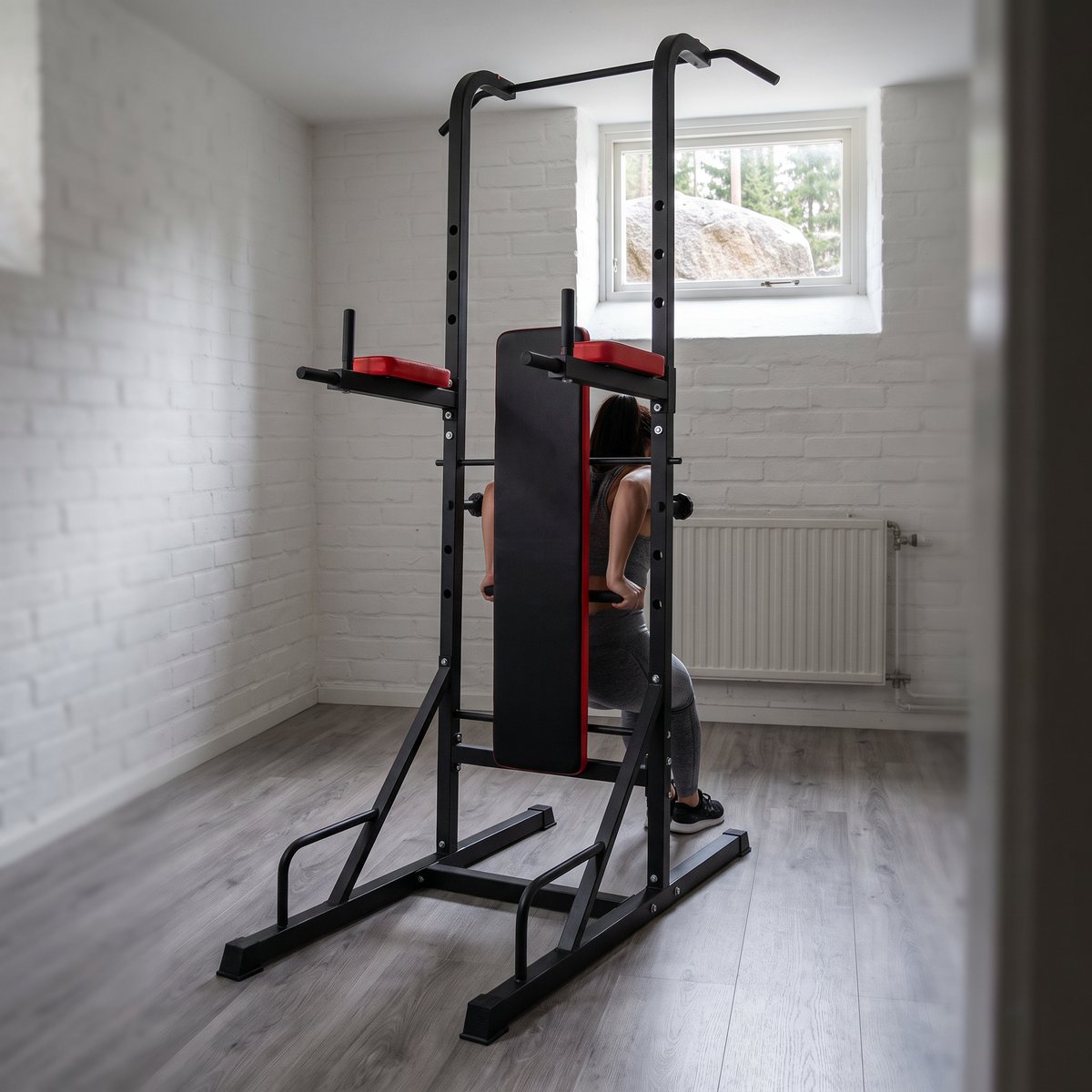 inSPORTline Power Tower X150 med bänk i ett vitt svenskt källarrum med fönster mot granitblock och gran