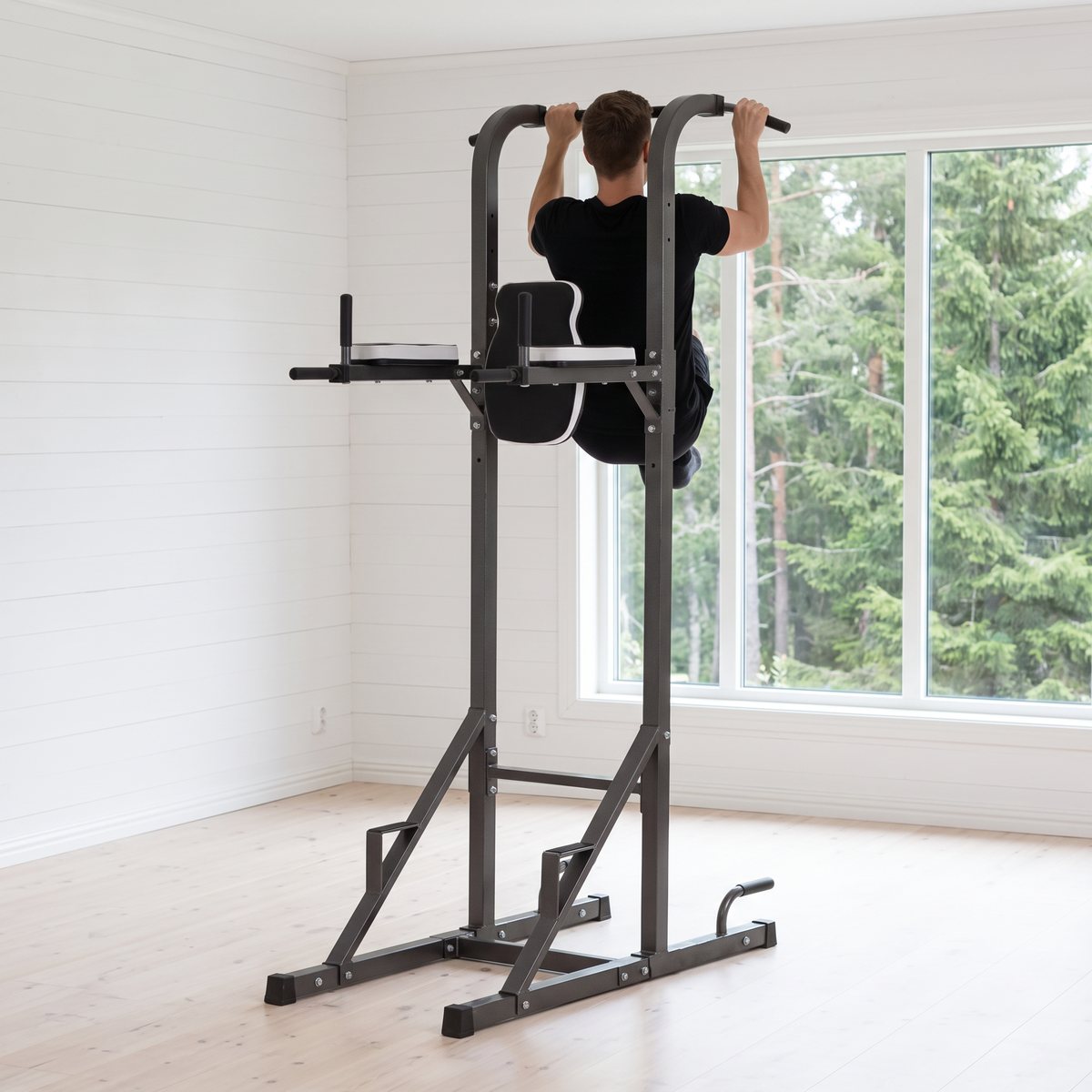 Toorx WBX 70 Power Tower där en person gör pullups i ett ljust svenskt hemmagym med utsikt mot tallskog