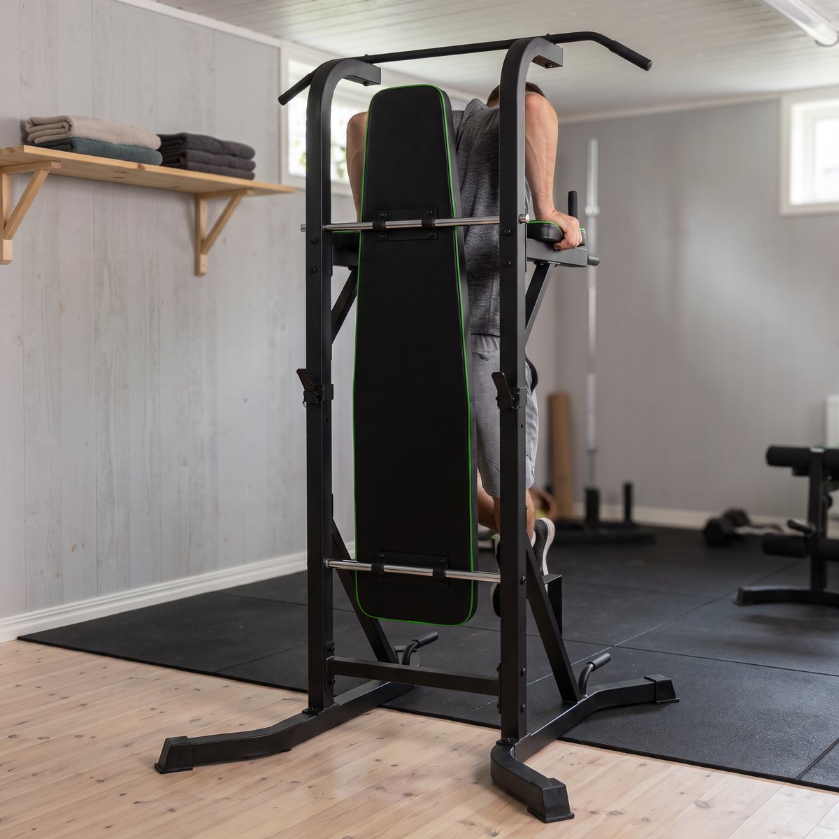 Tunturi PT60 Power Tower med bänkdyna där en person tränar i ett svenskt källargym med trägolv och gummimatta