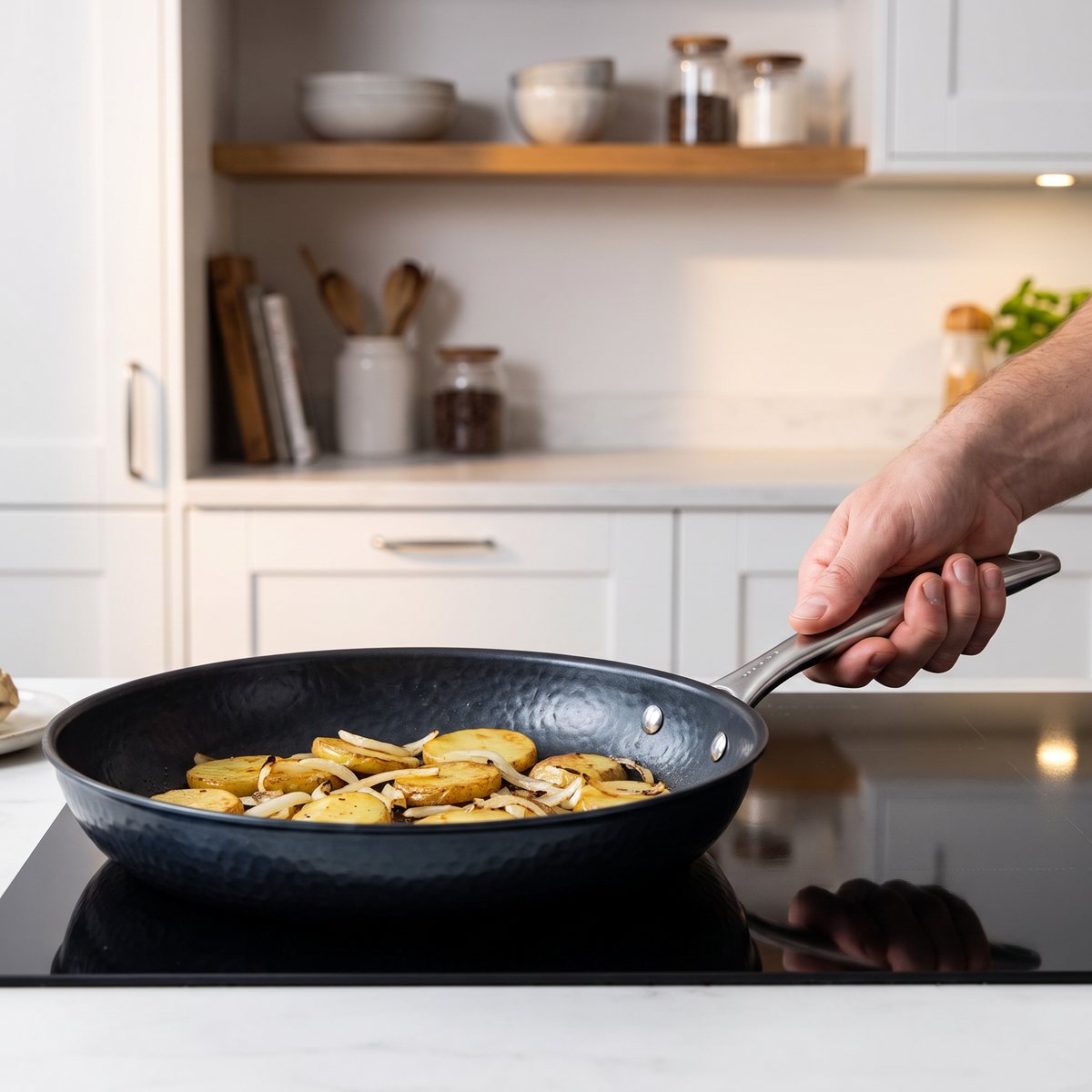 Satake hamrad kolstålspanna med stekt potatis och lök på en induktionshäll i ett svenskt kök