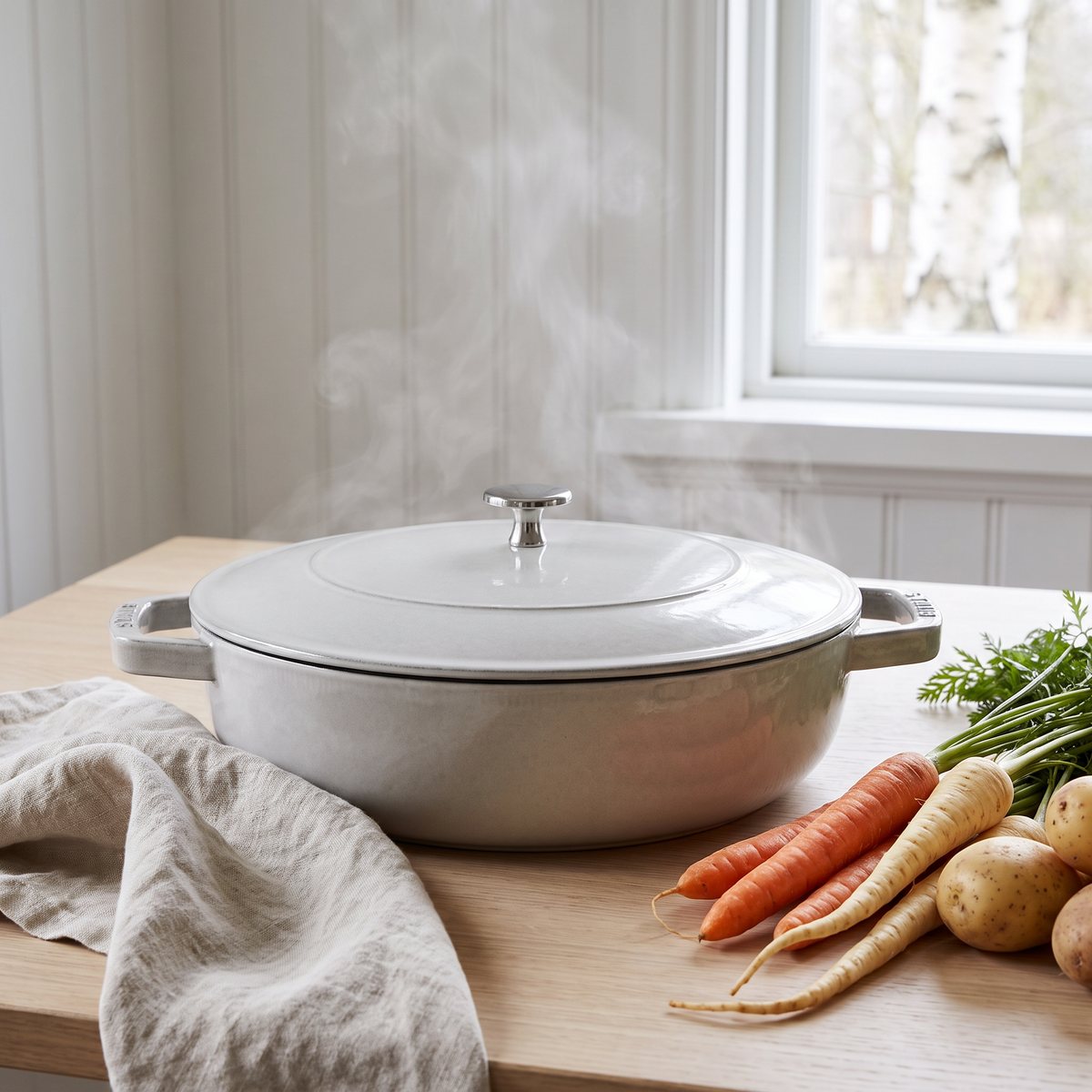 Staub Chistera sauteusepanna med lock på ett träbord i ett svenskt hem med rotfrukter