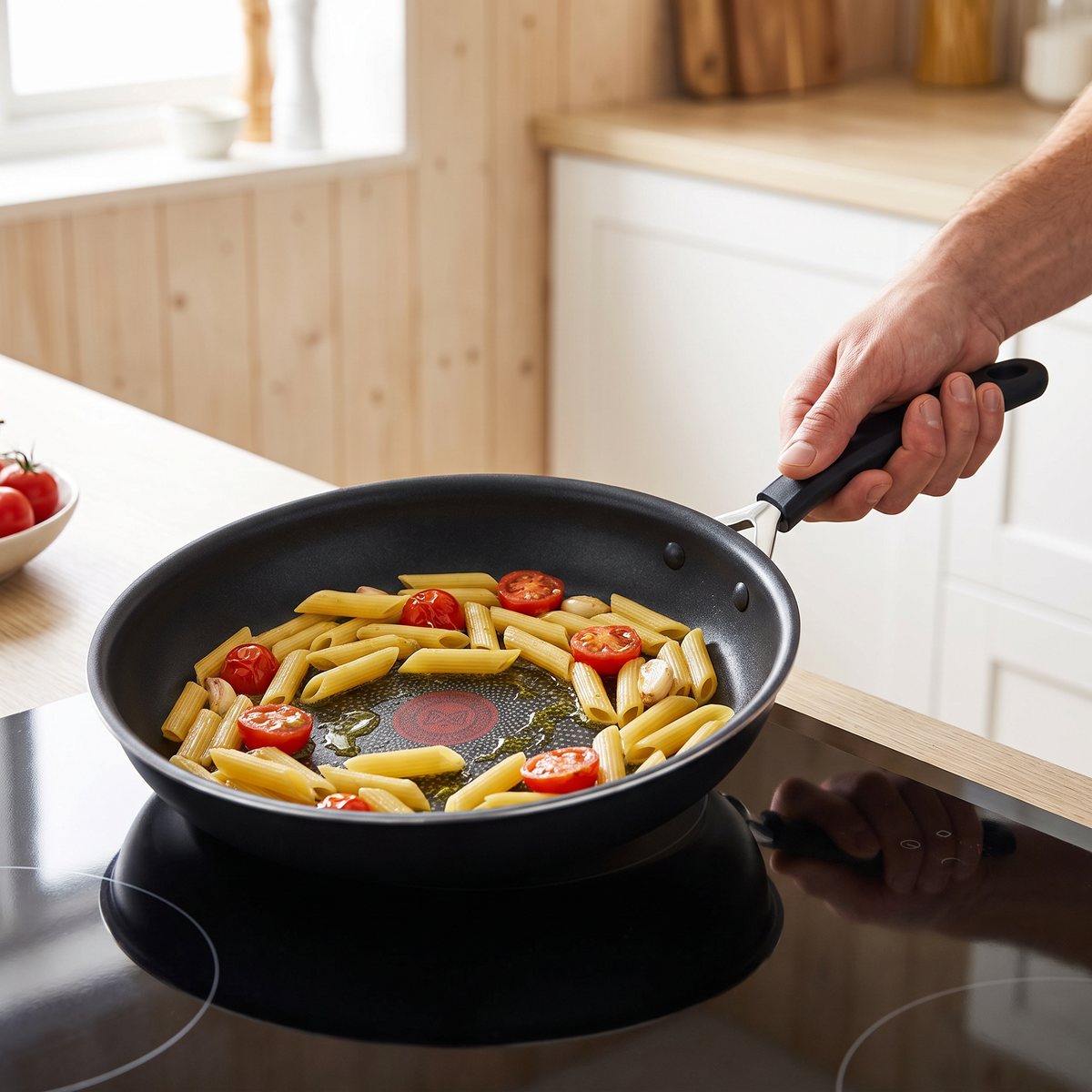 Jamie Oliver by Tefal Quick & Easy stekpanna med svart handtag på en induktionshäll i ett svenskt kök, med pasta och tomater som steks