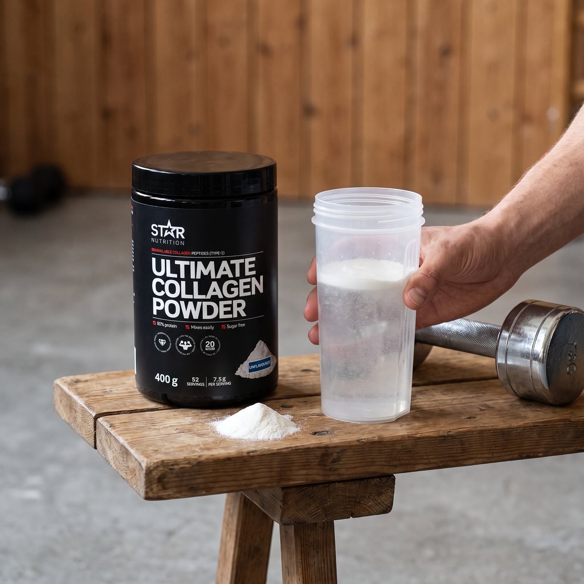Star Nutrition Ultimate Collagen Powder-burk på en träbänk i ett svenskt hemmagym med shaker och hantel