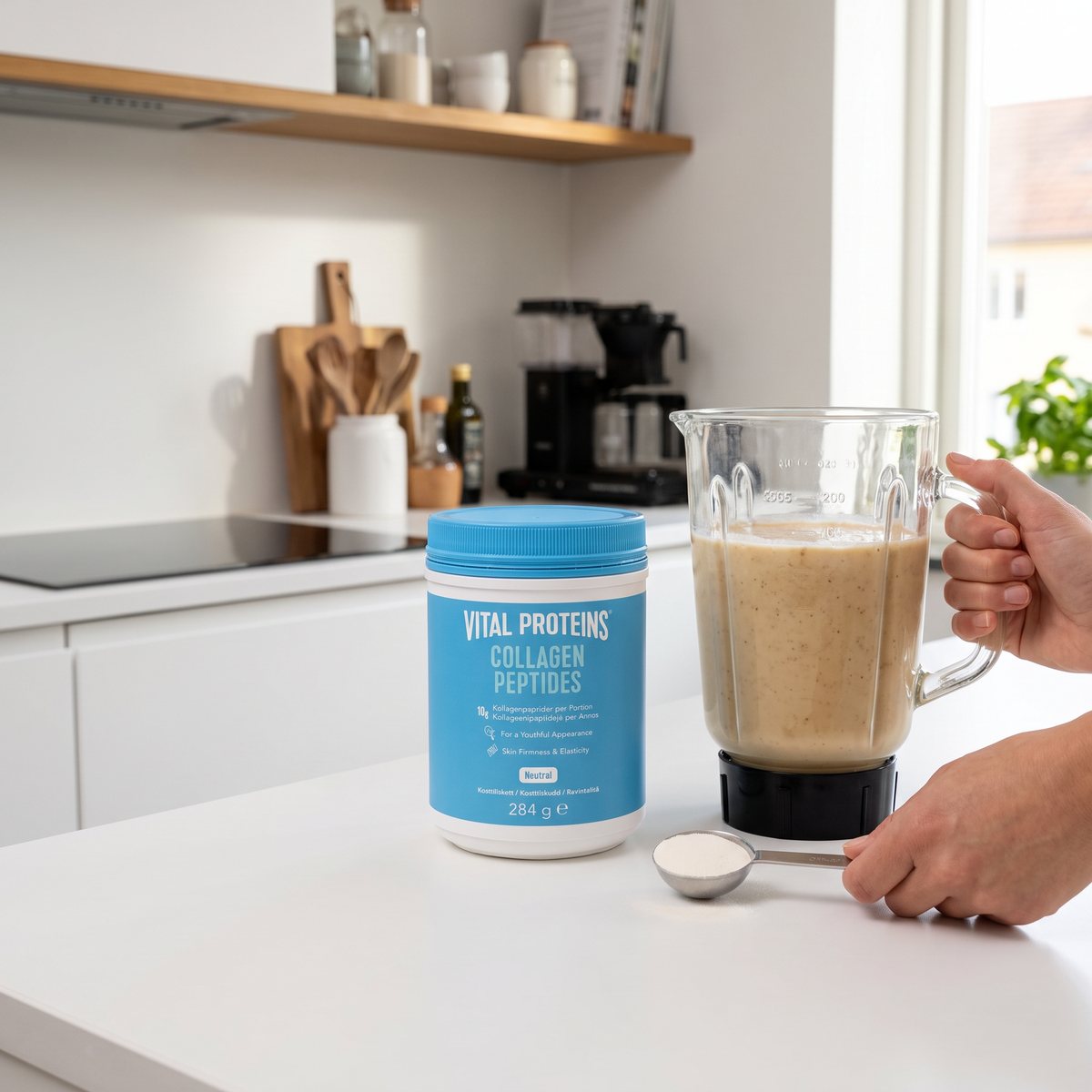 Vital Proteins Collagen Peptides-burk på en vit köksbänk i ett svenskt kök med en smoothie i mixern och en mått med pulver