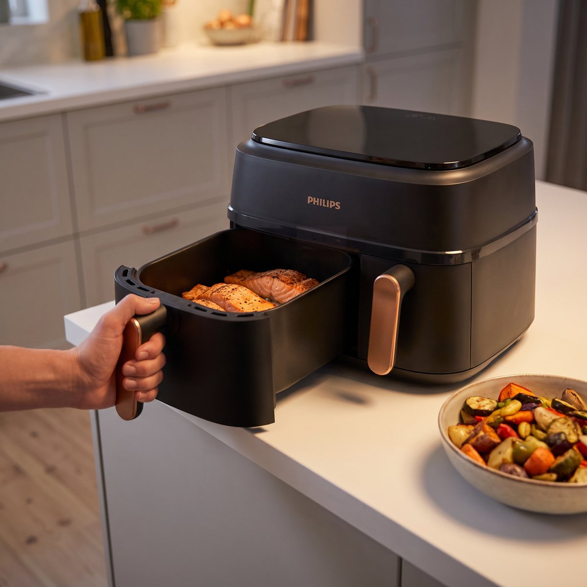 Philips NA352/00 med den stora korgen utdragen och lax i, bredvid en skål rostade grönsaker i ett svenskt kök