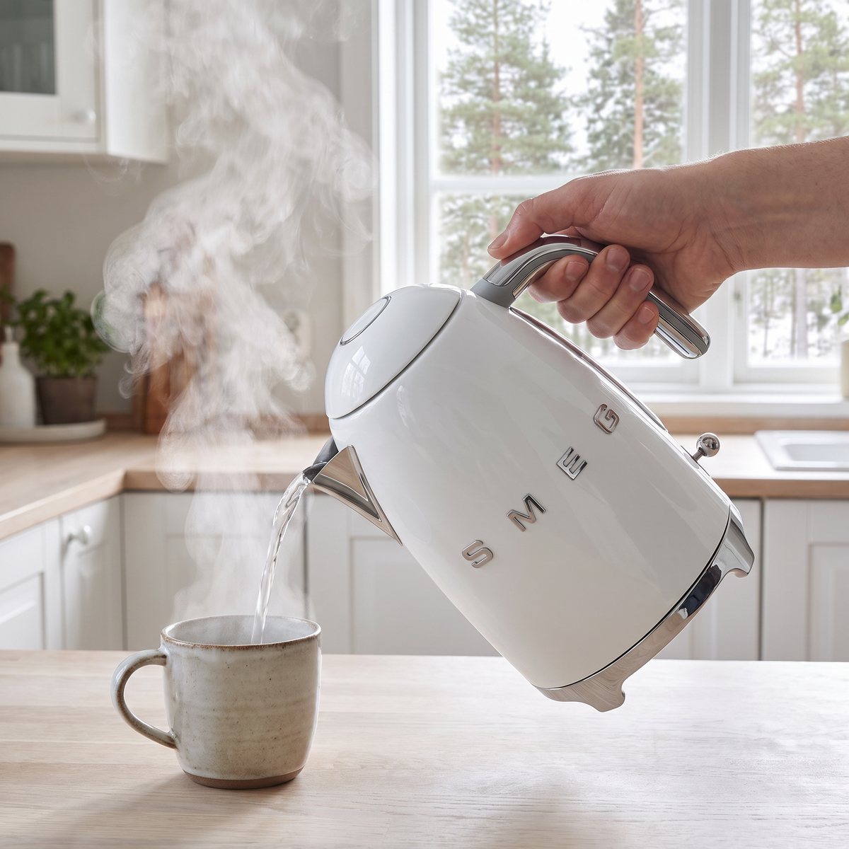 Smeg KLF03 vattenkokare som häller hett vatten i en mugg i ett ljust svenskt kök