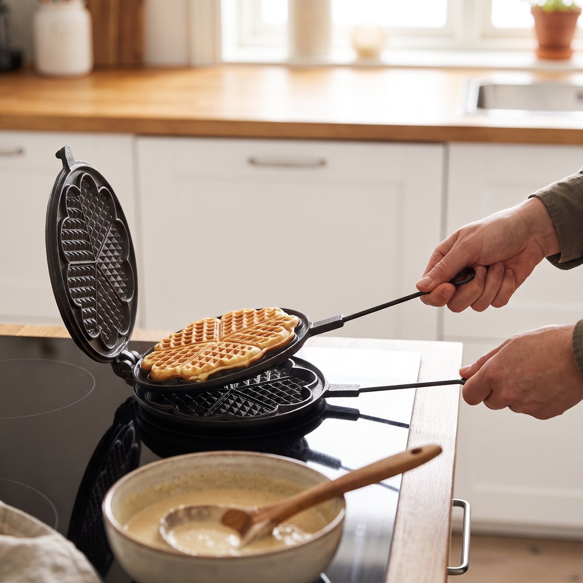 Skeppshults våffeljärn i gjutjärn med färdig hjärtvåffla på en häll i ett svenskt kök