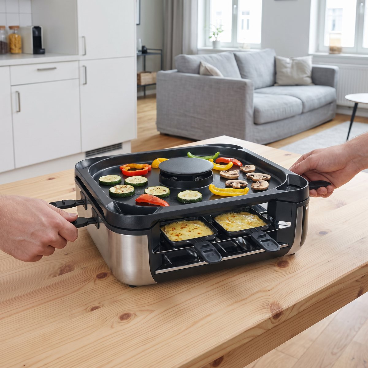 Severin RG 2379 Smokeless med grönsaker på plattan och ost i pannorna på ett köksbord i en svensk lägenhet