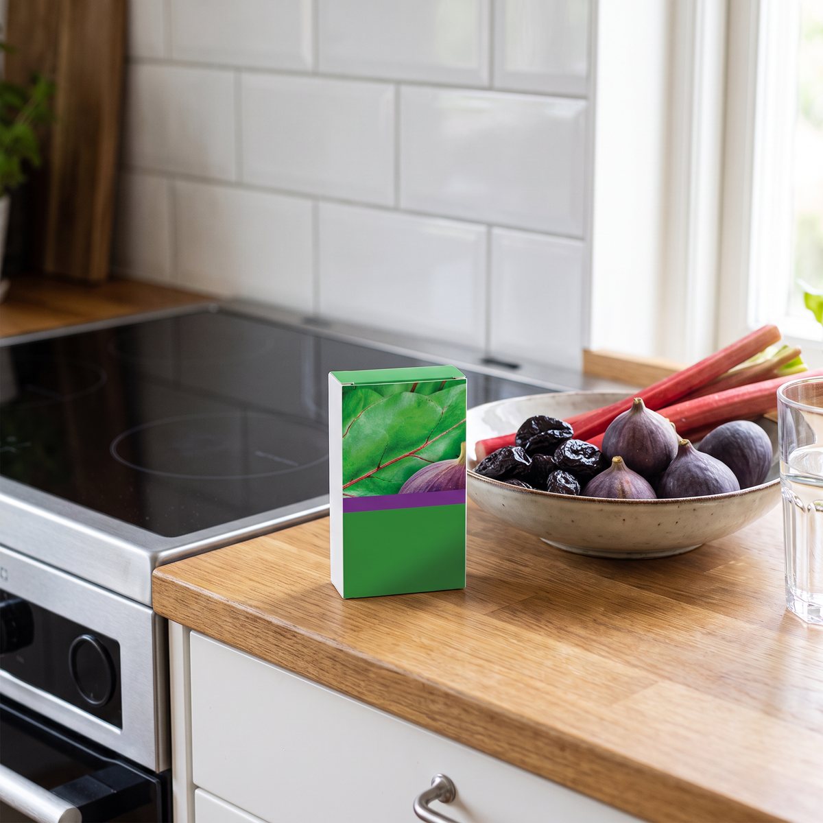 Förpackning Frukt & Fibrer från Ortis på en köksbänk med fikon, katrinplommon och rabarber vid en induktionshäll i ett svenskt kök