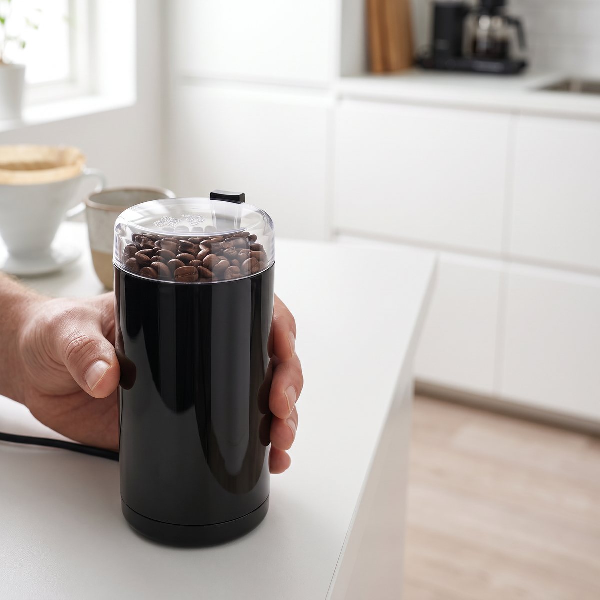 Svart Bosch-kaffekvarn med genomskinligt lock fylld med kaffebönor i ett svenskt kök