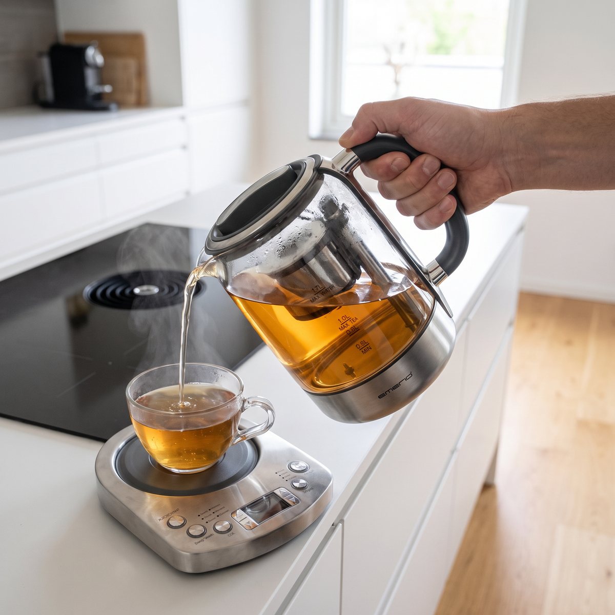 Emerio tekokare som hälls upp i en glaskopp i ett svenskt kök med induktionshäll