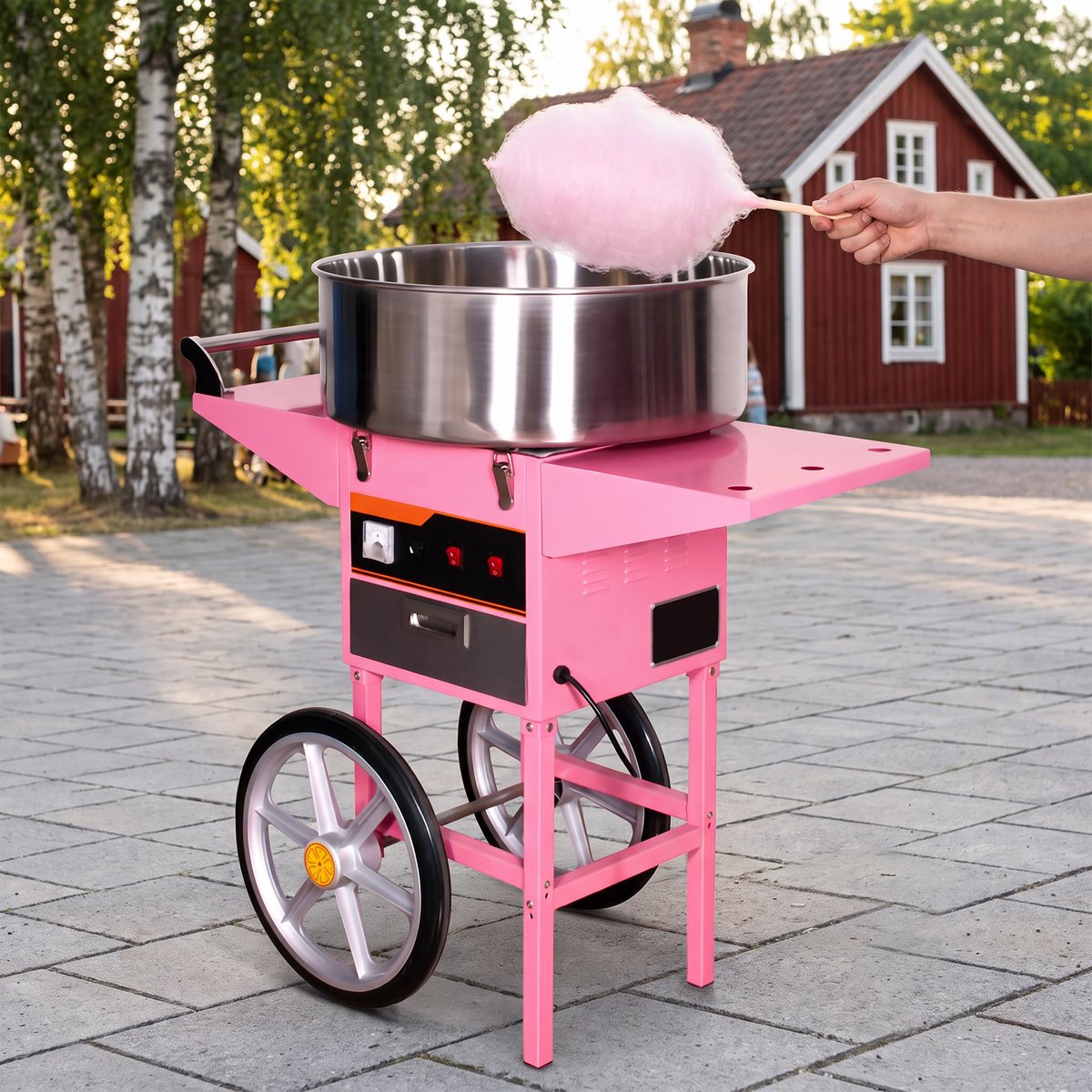 Rosa sockervaddsmaskin på vagn med hjul på ett torg vid en svensk sommarfest
