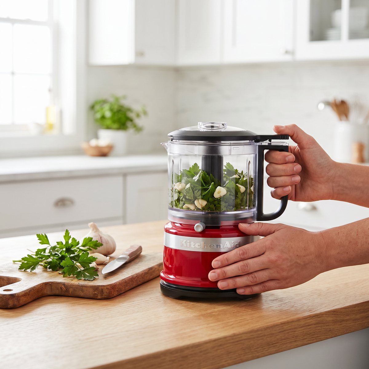 Röd KitchenAid minihackare med persilja och vitlök på en köksbänk i ett svenskt kök