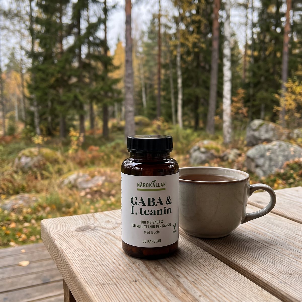 Närokällan GABA + L-teanin på ett furubord på en svensk veranda i höstskog med en tekopp bredvid