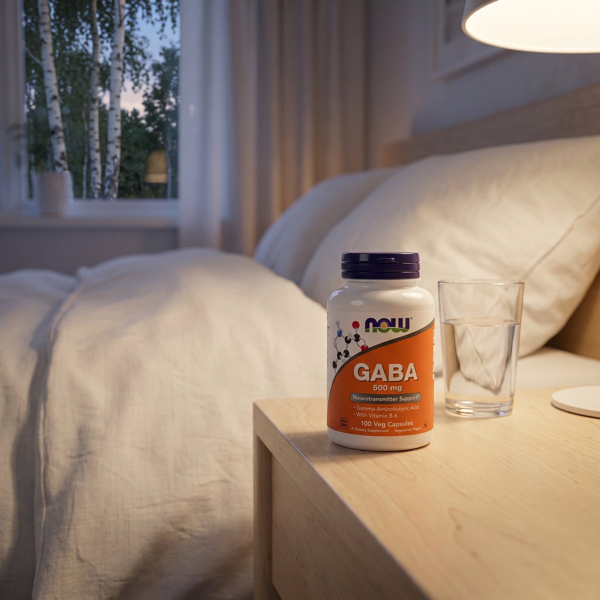NOW GABA 500 mg-burken på ett nattduksbord av ljus björk bredvid ett vattenglas i ett svenskt sovrum på kvällen
