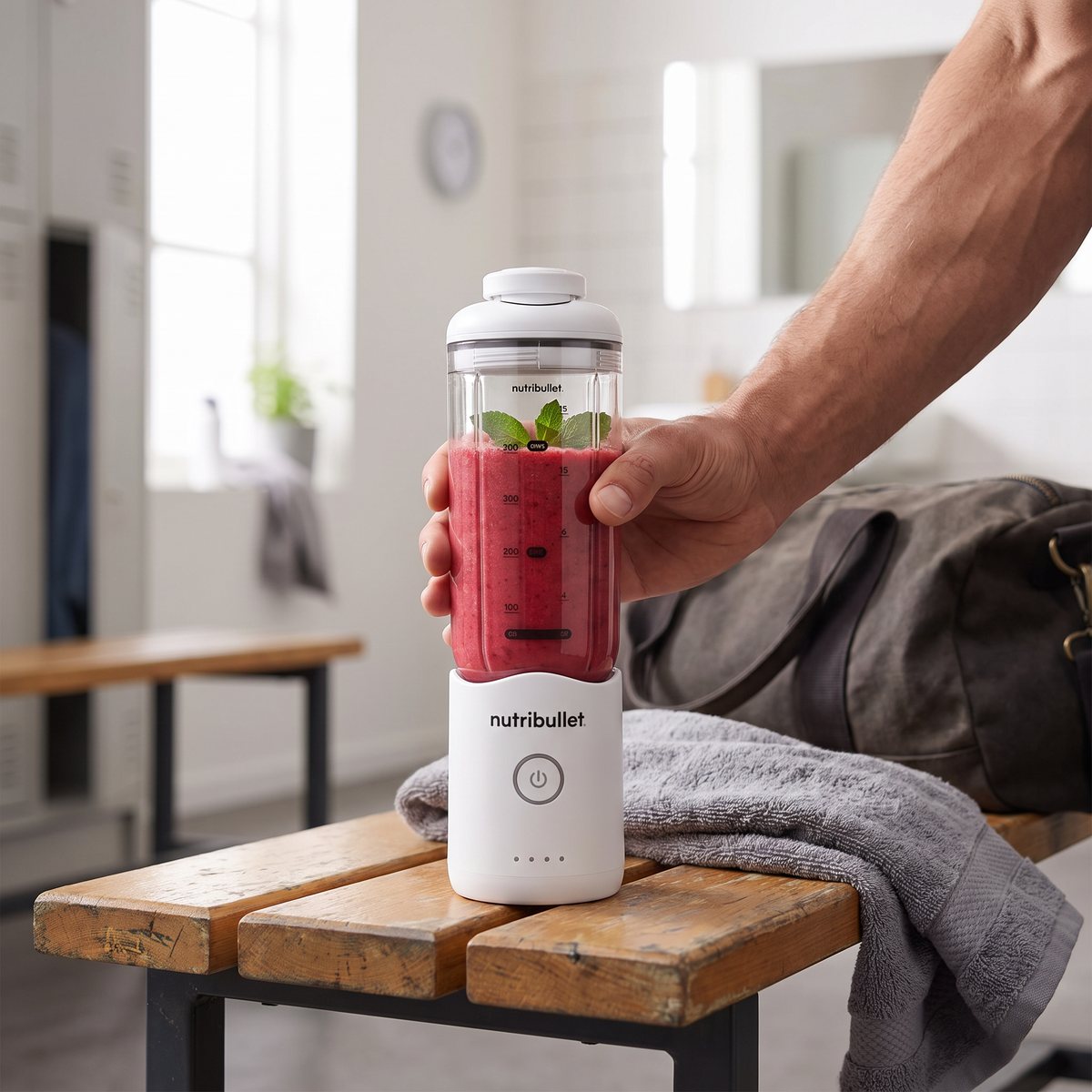 Hand håller Nutribullet Flex med rosa smoothie på en träbänk i ett svenskt omklädningsrum