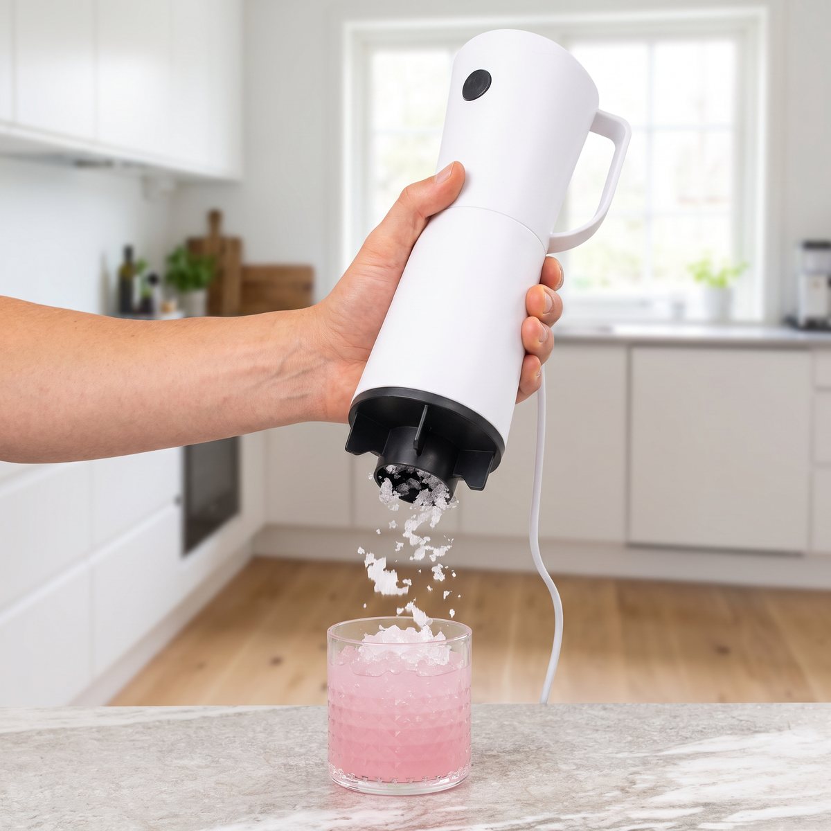 KitchPro handhållen iskross i vitt som krossar is ner i ett glas med rosa dryck, i ett svenskt kök
