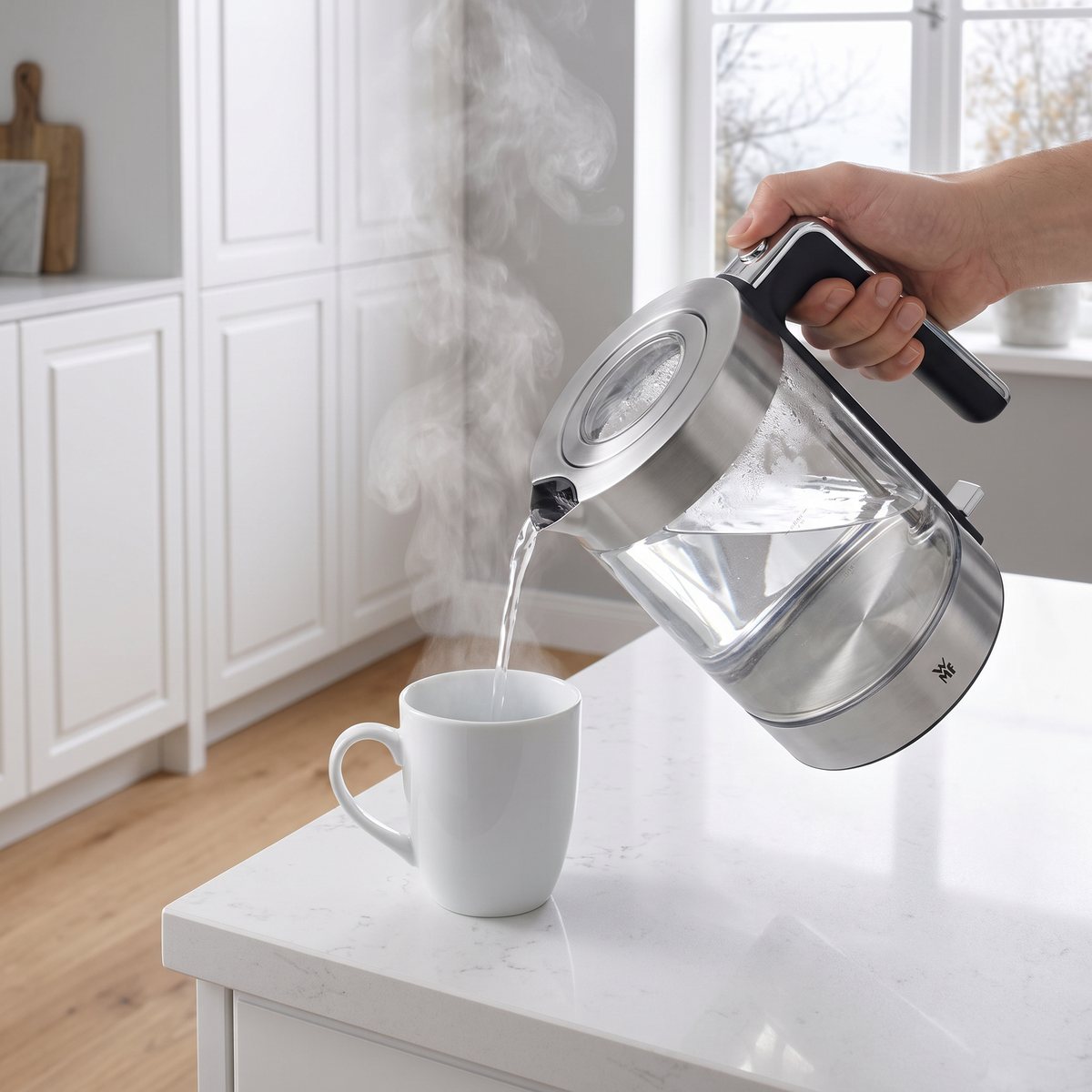 Hand som häller hett vatten ur WMF Lono Glas i ett ljust svenskt kök