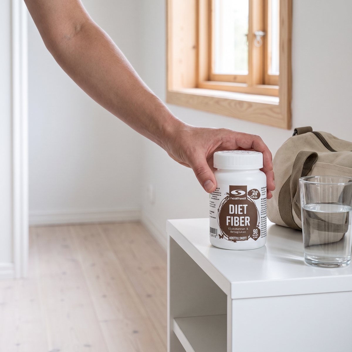 Burk med Healthwell Diet Fiber hållen i handen i en svensk hall bredvid ett glas vatten
