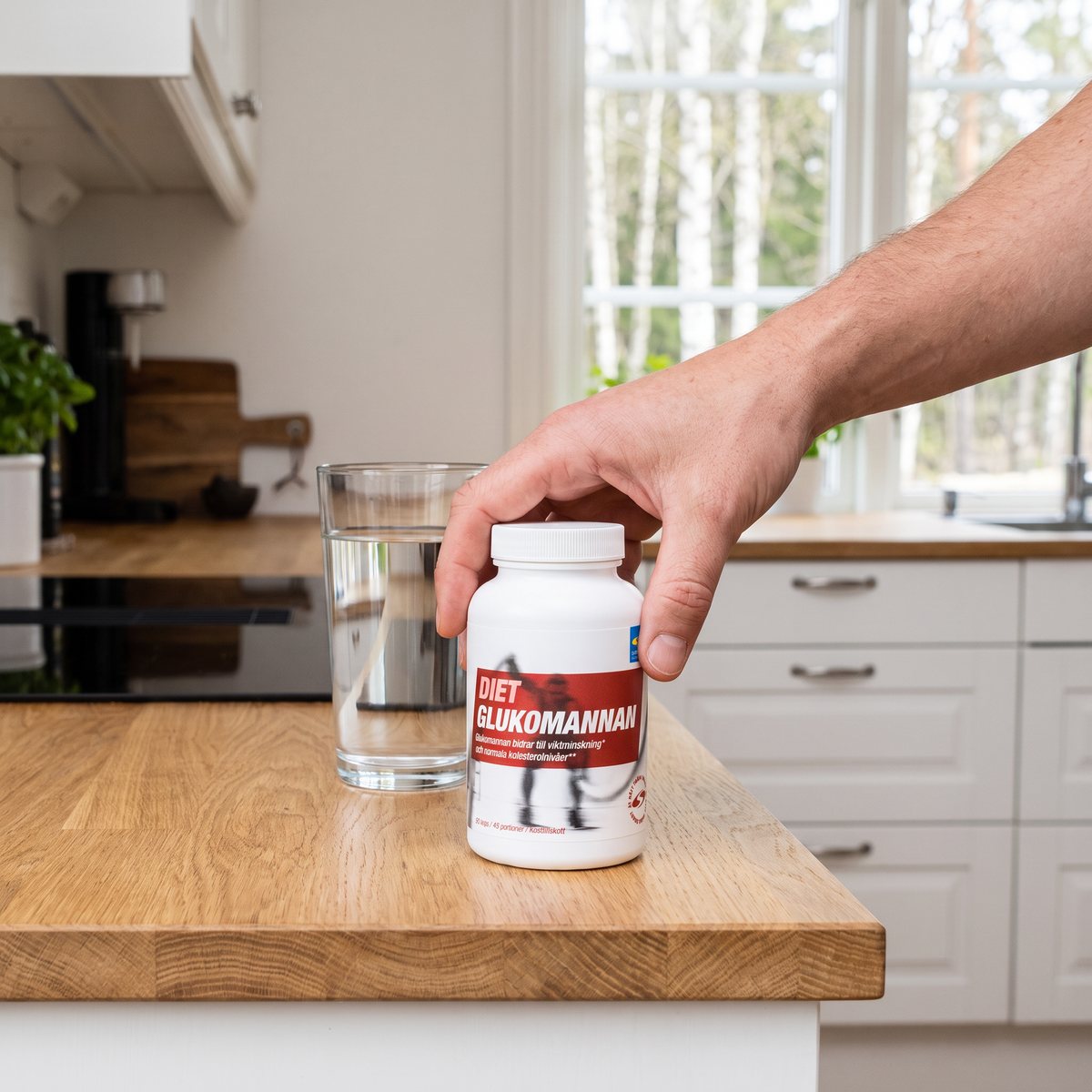 Burk med Svenskt Kosttillskott Diet Glukomannan på en köksbänk bredvid ett glas vatten i ett svenskt kök