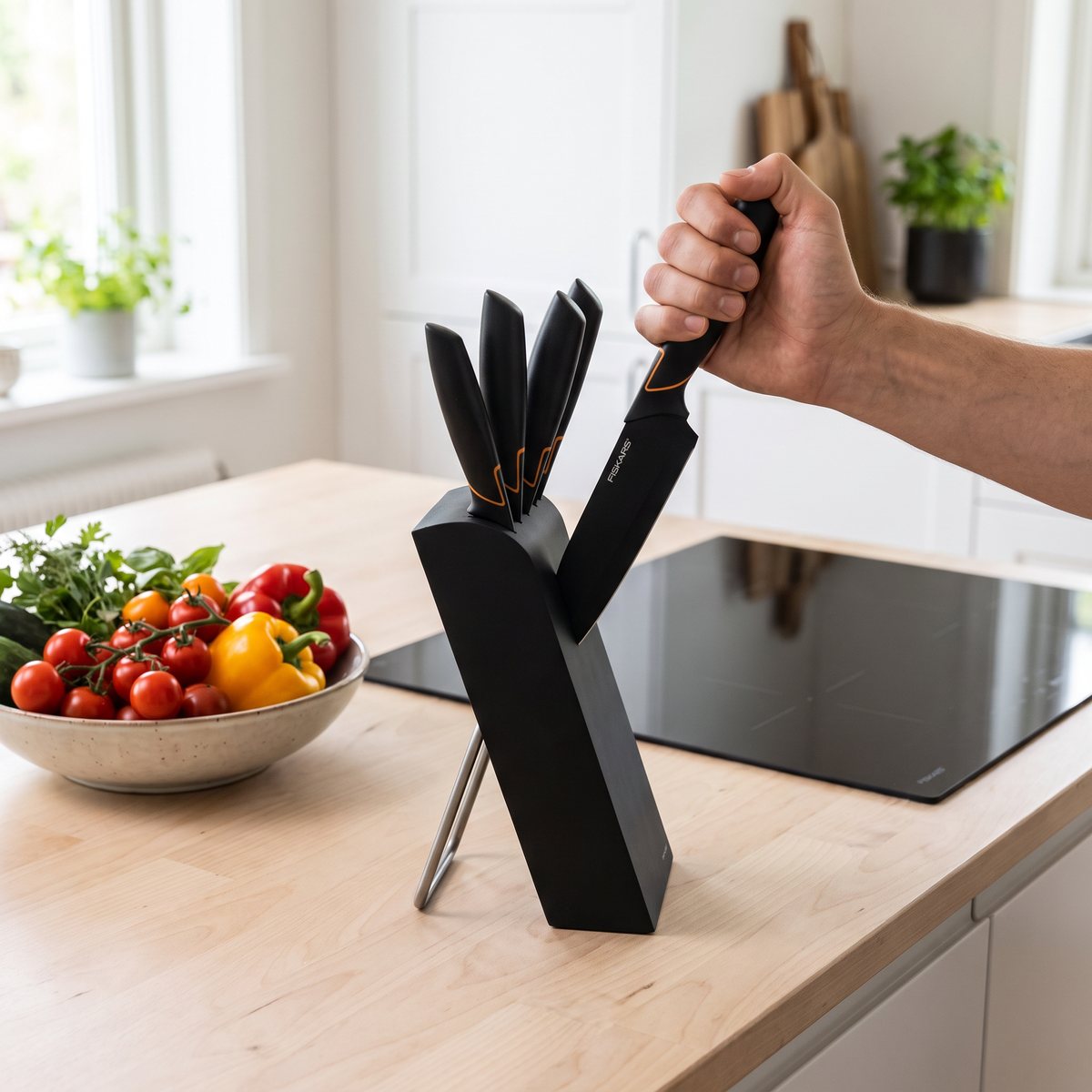 Fiskars Edge knivblock i svart där en kniv dras ur blocket på en köksbänk i svenskt kök