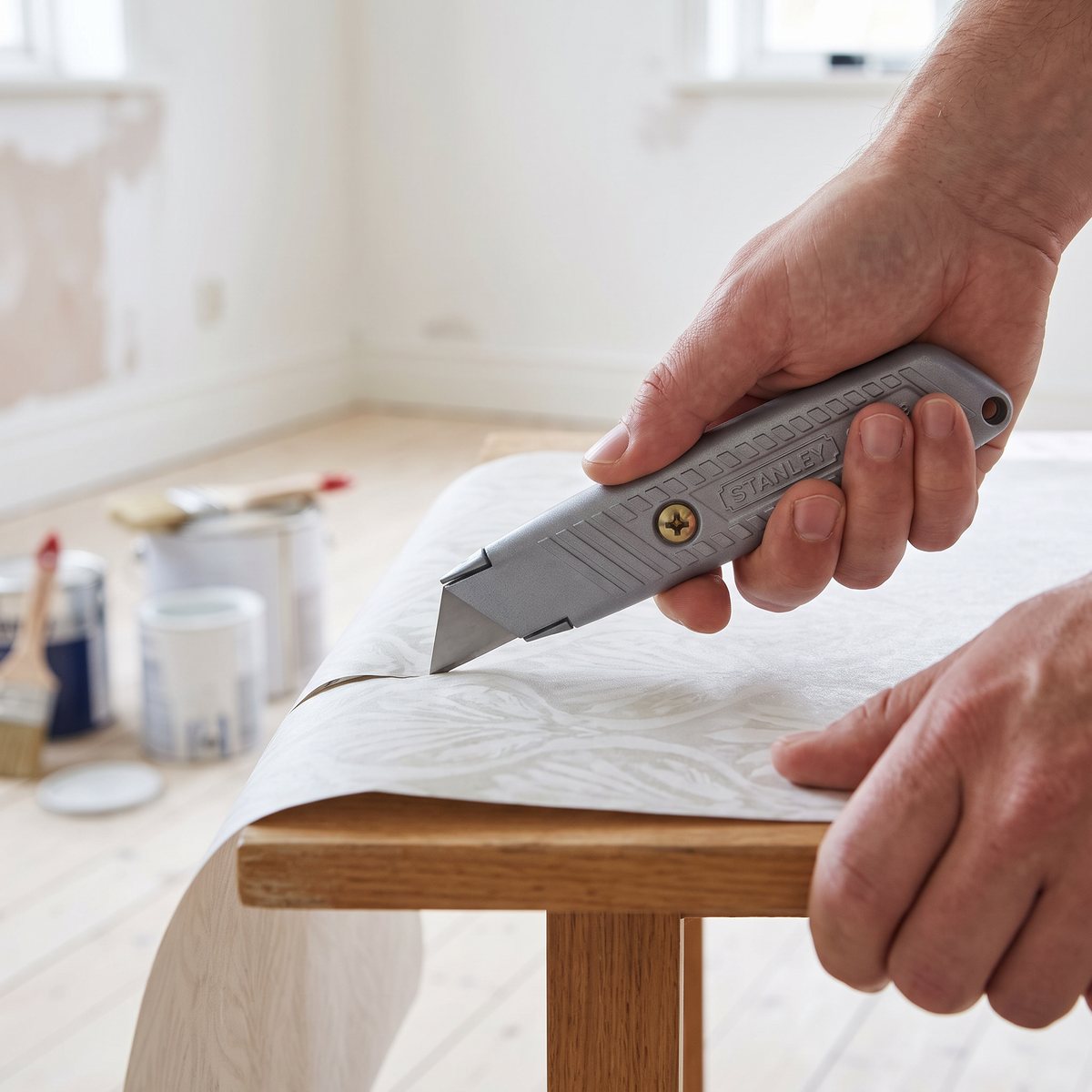 Stanley universalkniv med fast blad skär tapet på ett bord i ett svenskt hem under renovering