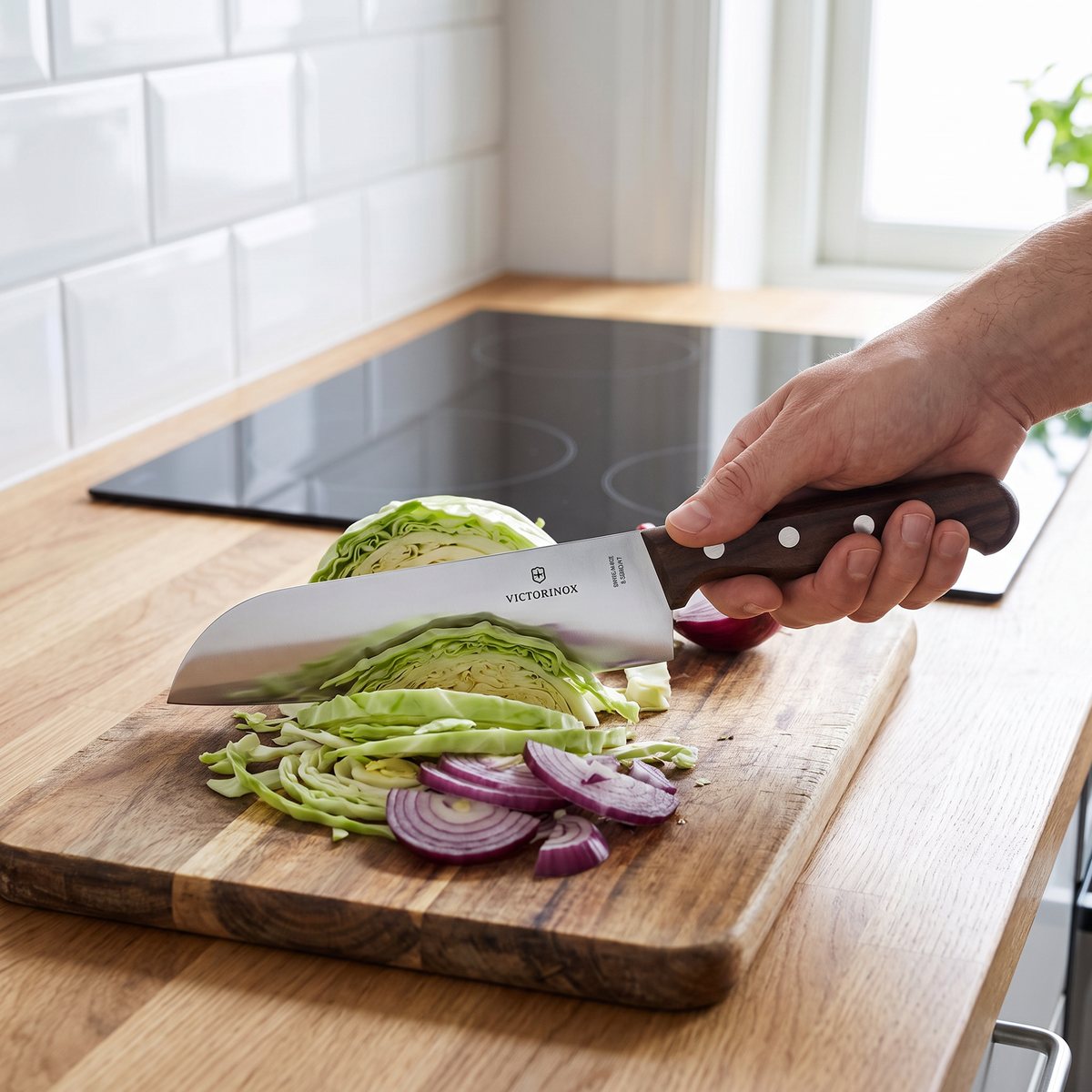 Victorinox Wood santokukniv med träskaft som skär vitkål och rödlök i ett svenskt kök med induktionshäll