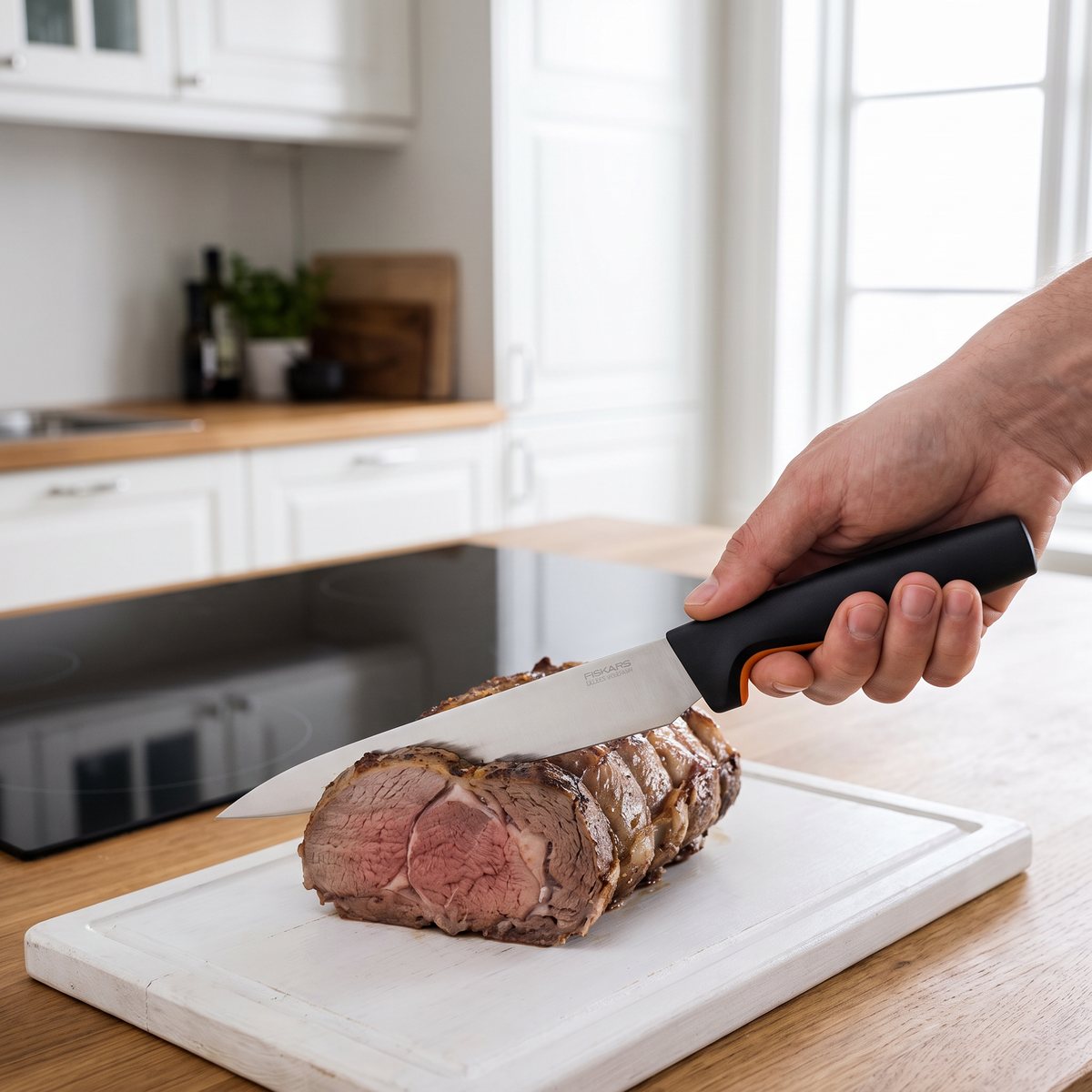 Fiskars Functional Form förskärare skär en lammstek på en vit skärbräda i ett svenskt kök