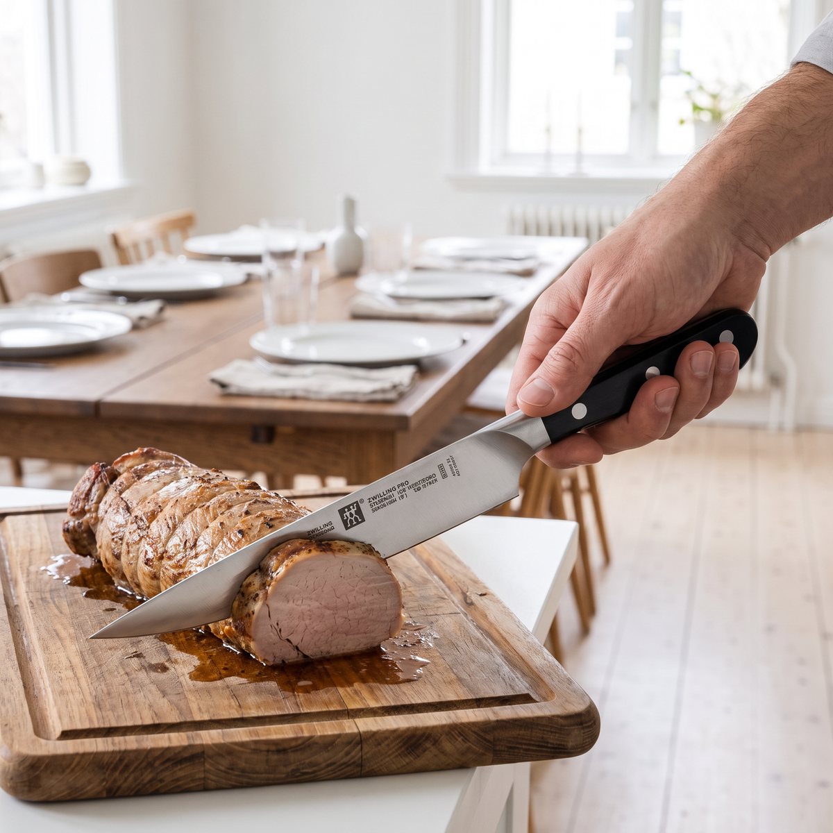 Zwilling Pro förskärare skär en fläskfilé vid ett dukat bord i ett ljust svenskt hem