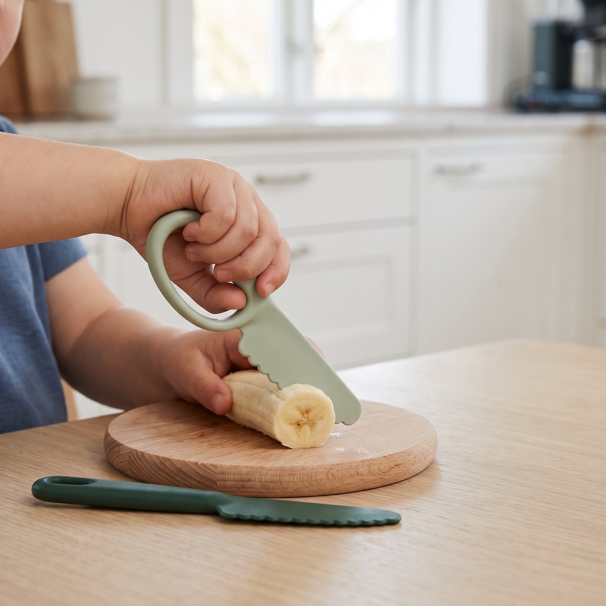Barn som skär banan med Liewood Riven knivset i ett svenskt kök