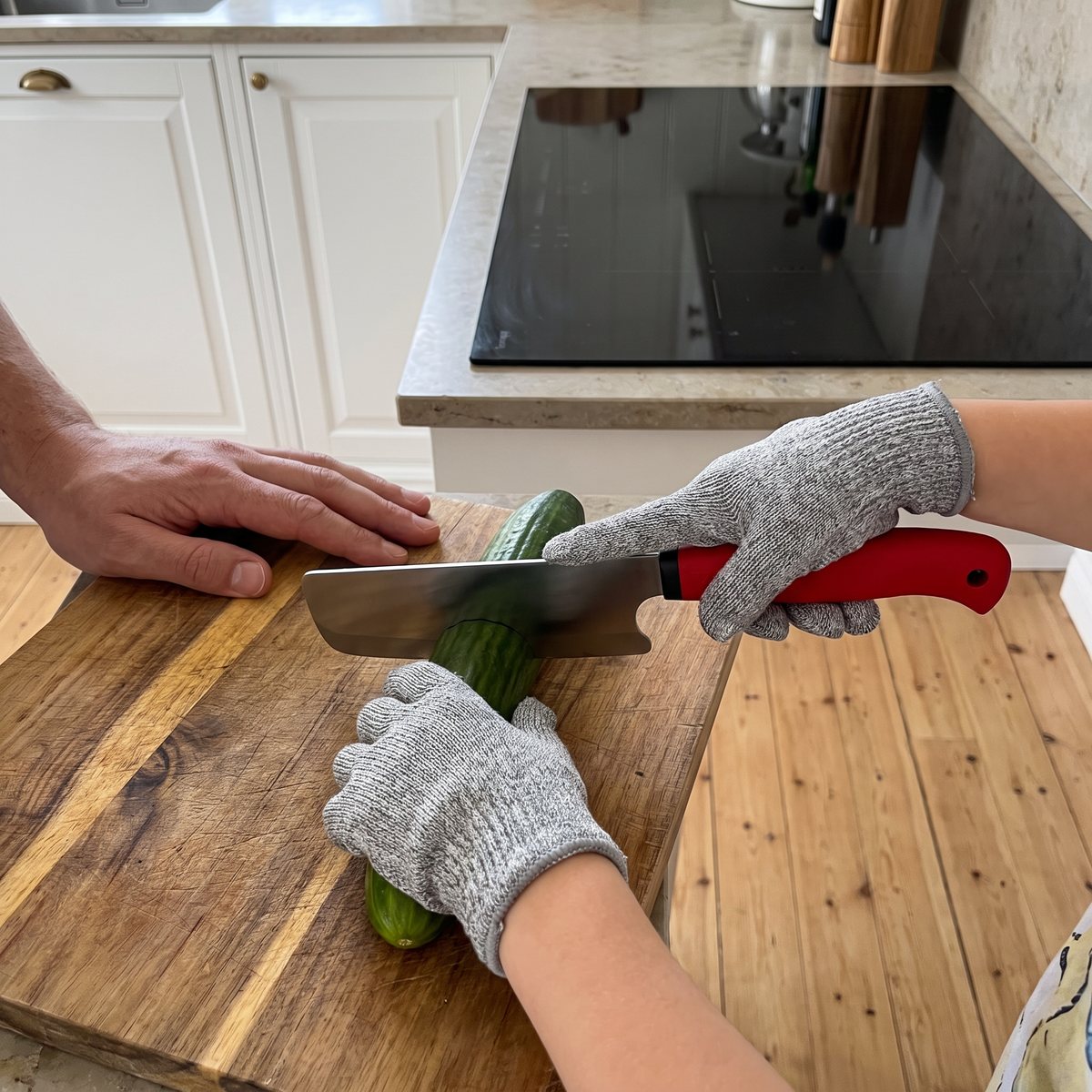 Barn som skär gurka med Satake Kids barnkniv och skärsäker handske i ett svenskt kök