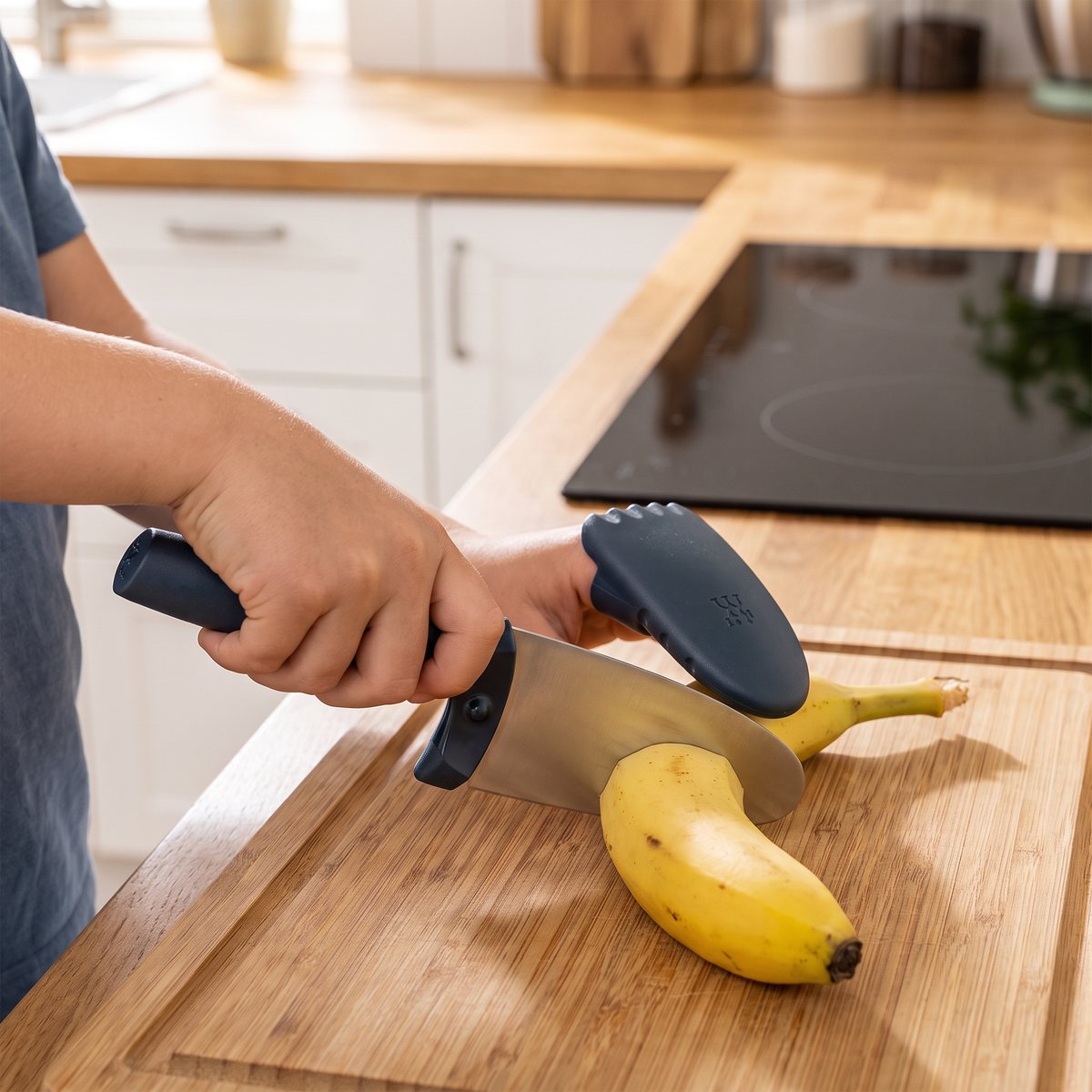 Barn som skär banan med Zwilling Twinny kockkniv och fingerskydd i ett svenskt kök
