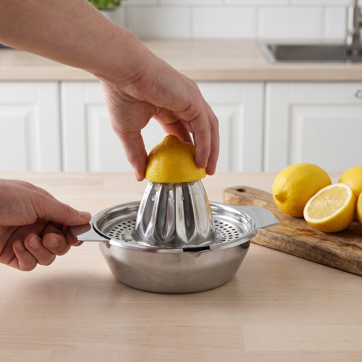 Citronhalva vrids mot Dorre Clea citruspress i rostfritt stål på en bänkskiva av ljust trä i ett svenskt kök.