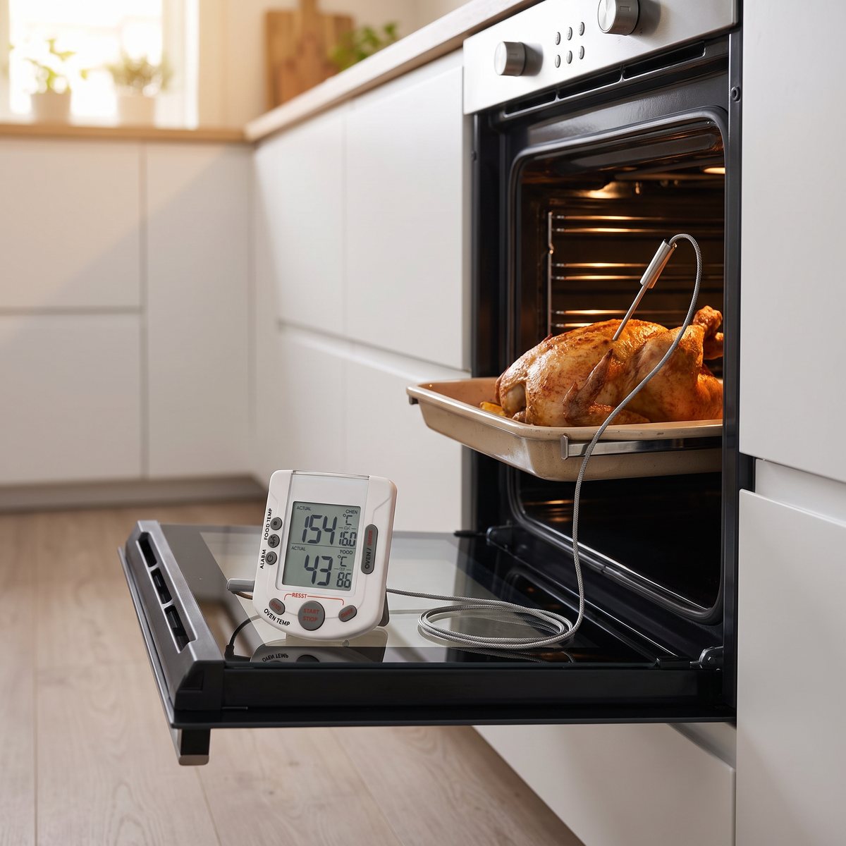 TFA stek- och ugnstermometer med digital display och sladdsond i en kyckling i ugnen i ett svenskt kök
