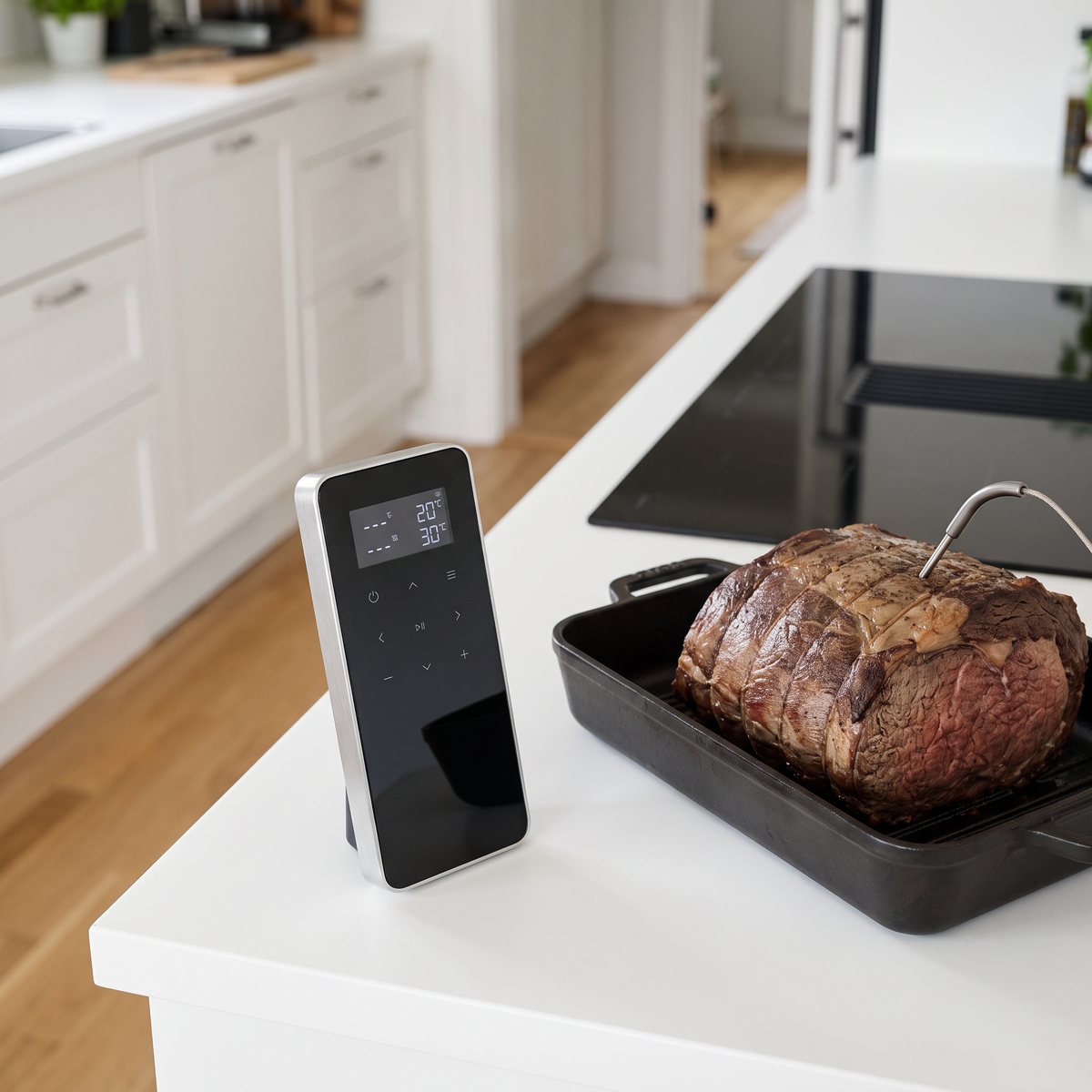Typhur Sync One, en smal trådlös stektermometer med svart glasfront, bredvid en stek i en gjutjärnsform i ett svenskt kök med induktionshäll