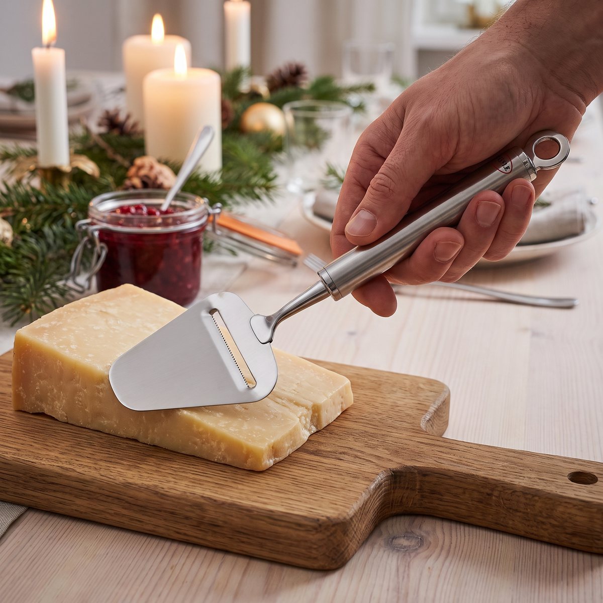 Osthyvel i borstat stål på ett ostfat med hård ost på ett dukat bord i ett svenskt hem
